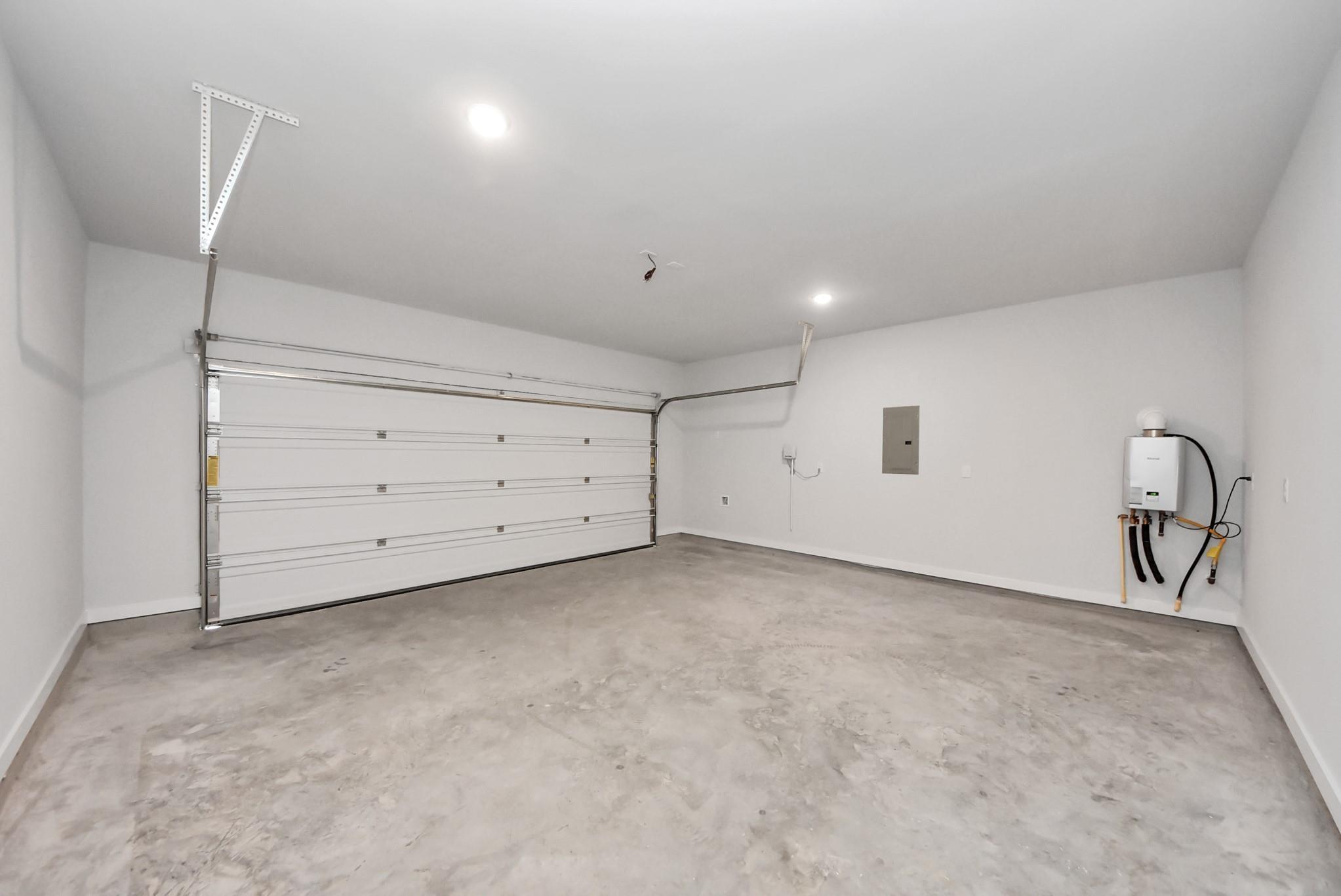 Clean 2-car garage with tankless water heater in The Blanco E floor plan at The Villages at WestPointe, Dayton, Texas.