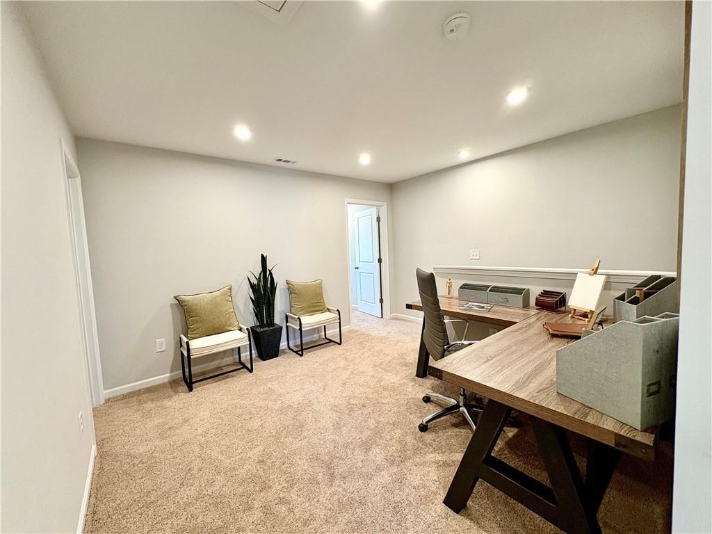 Modern home office with L-shaped wooden desk, ergonomic chair, armchairs, snake plant in The Monroe A, Emerson, Georgia
