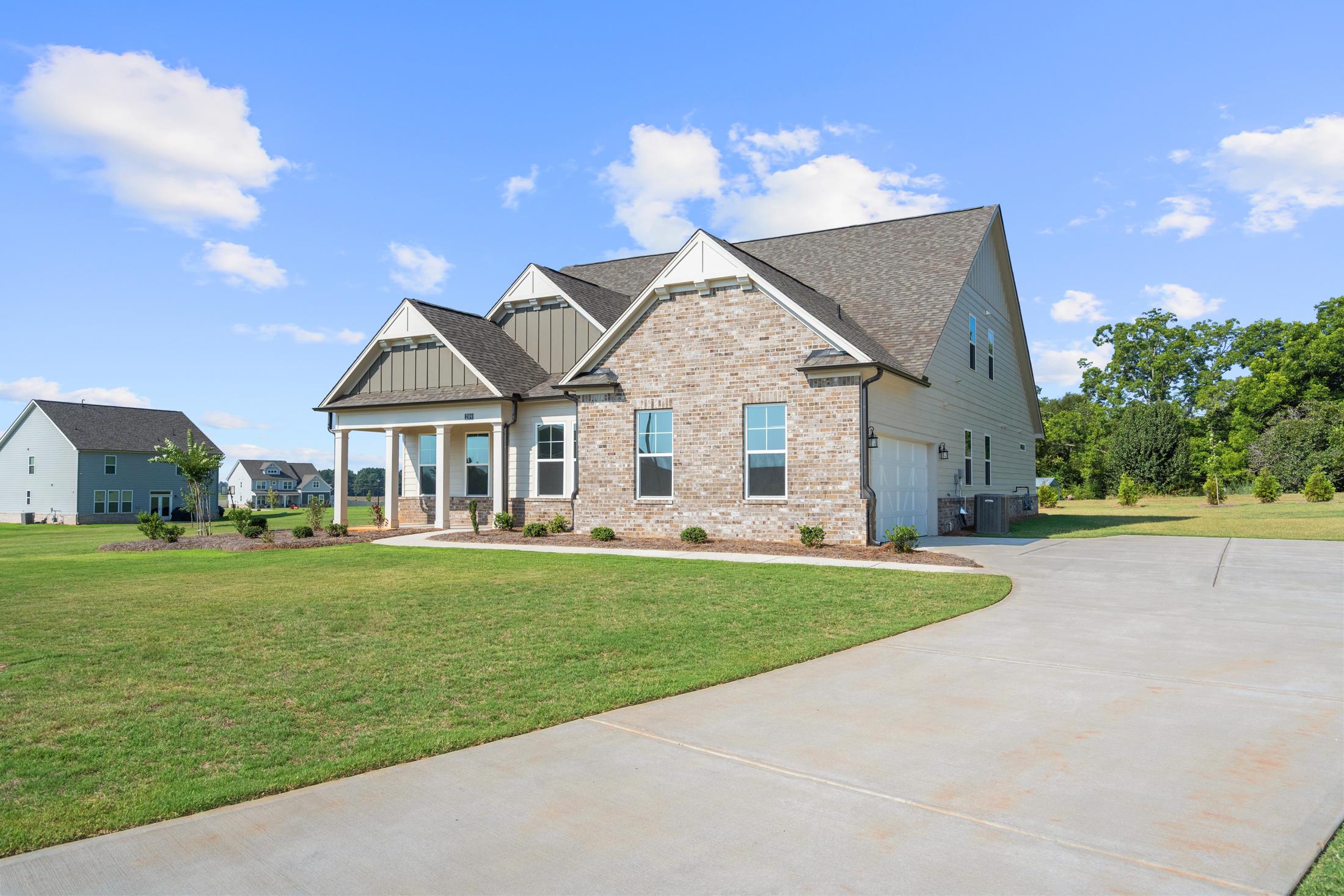 Craftsman-style home exterior at Everleigh in Locust Grove GA with covered porch, brick accents, and lush green lawn