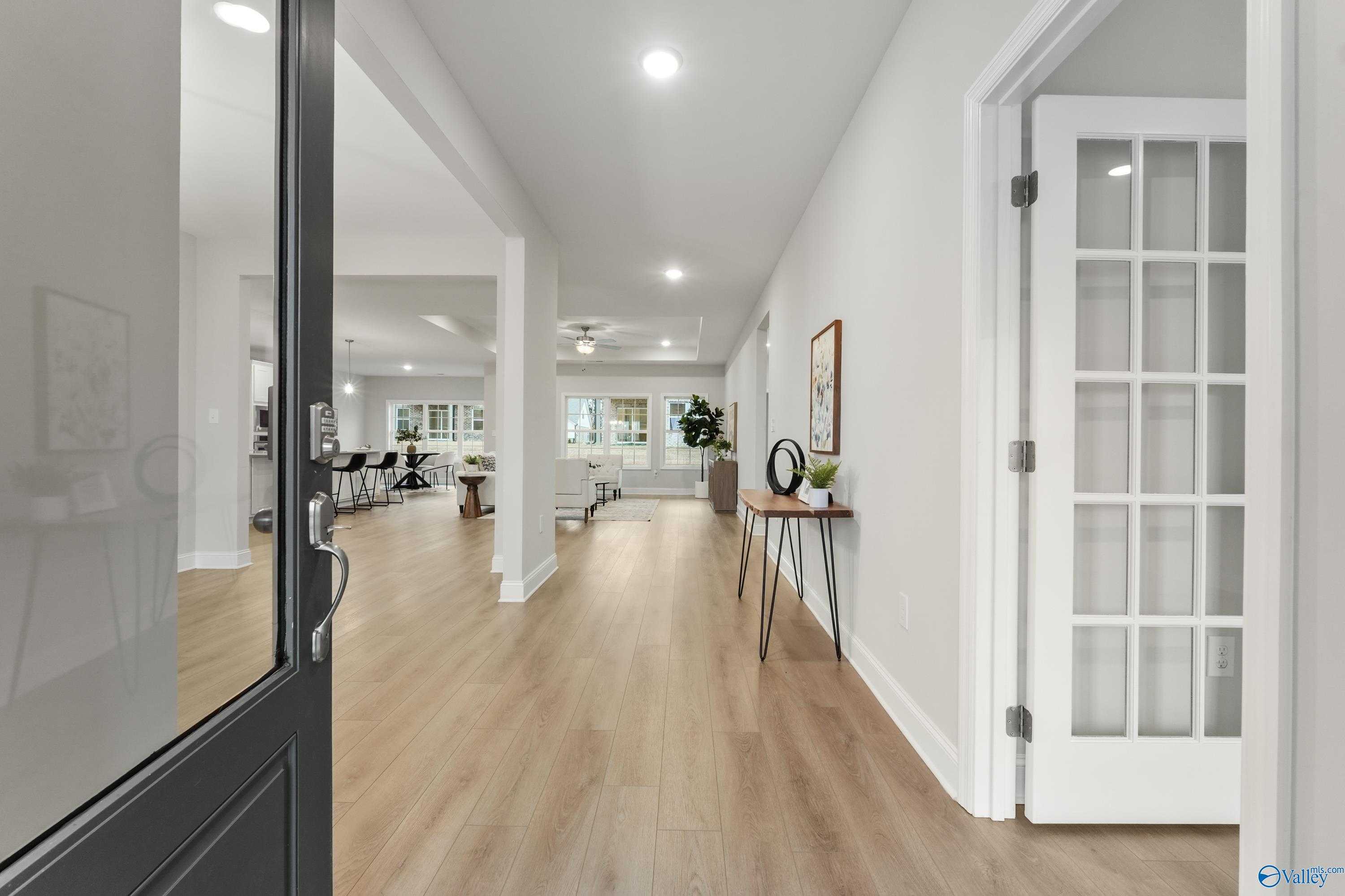Bright entry foyer with light oak hardwood floors, white walls, and open view to living area in Davidson Homes The Finleigh, Toney, Alabama