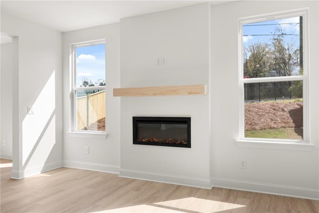 Bright living room with linear gas fireplace, oak mantel, and large windows overlooking backyard in Davidson Homes The Gavin E, Kennesaw, GA