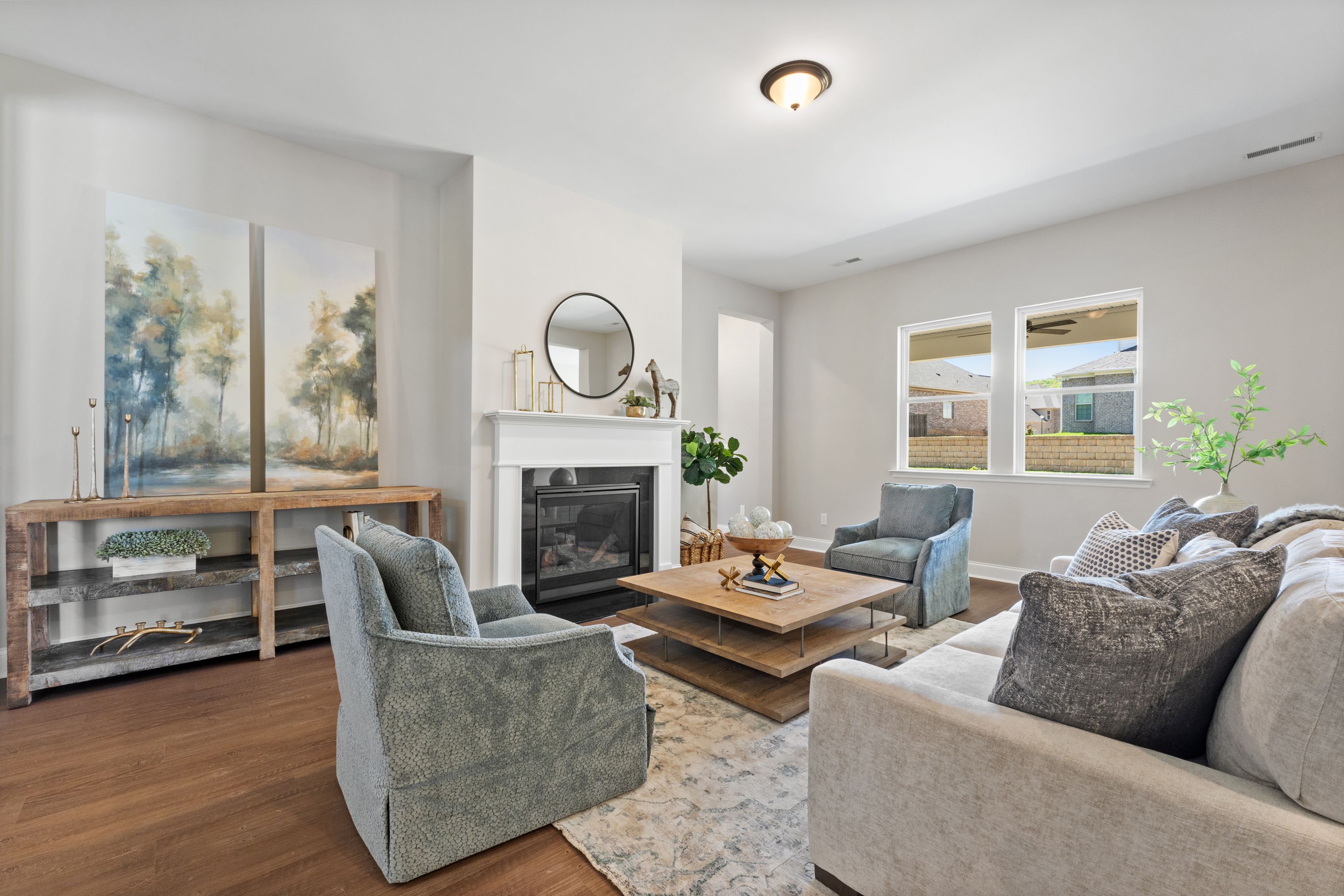 Spacious living room in The Haven D showcasing neutral gray sofa, armchairs, gas fireplace, abstract wall art, and hardwood floors