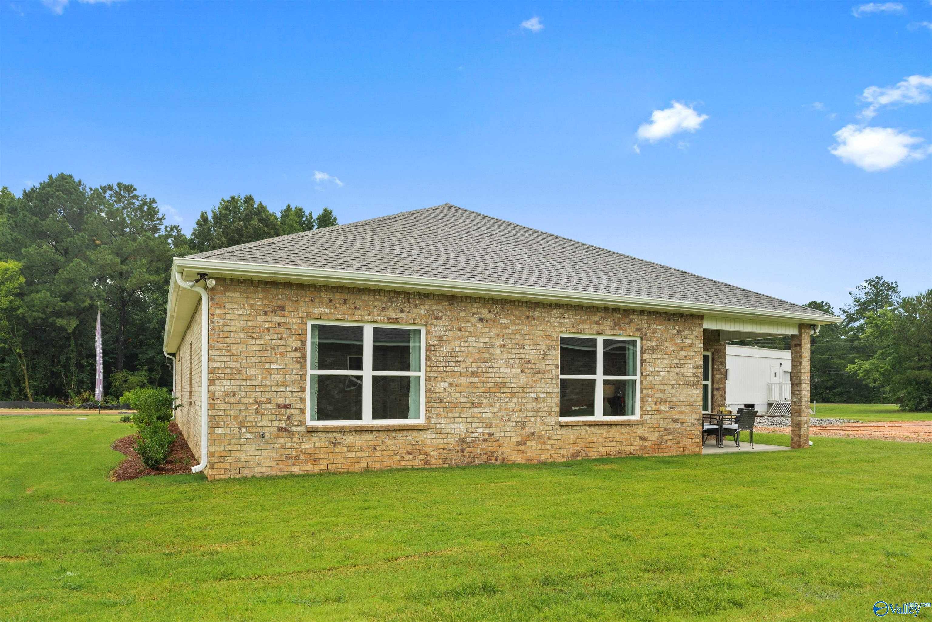 Side view of brick single-story The Daphne home with 2-car garage, lush green yard, Davidson Homes in Durham Farms, Harvest AL