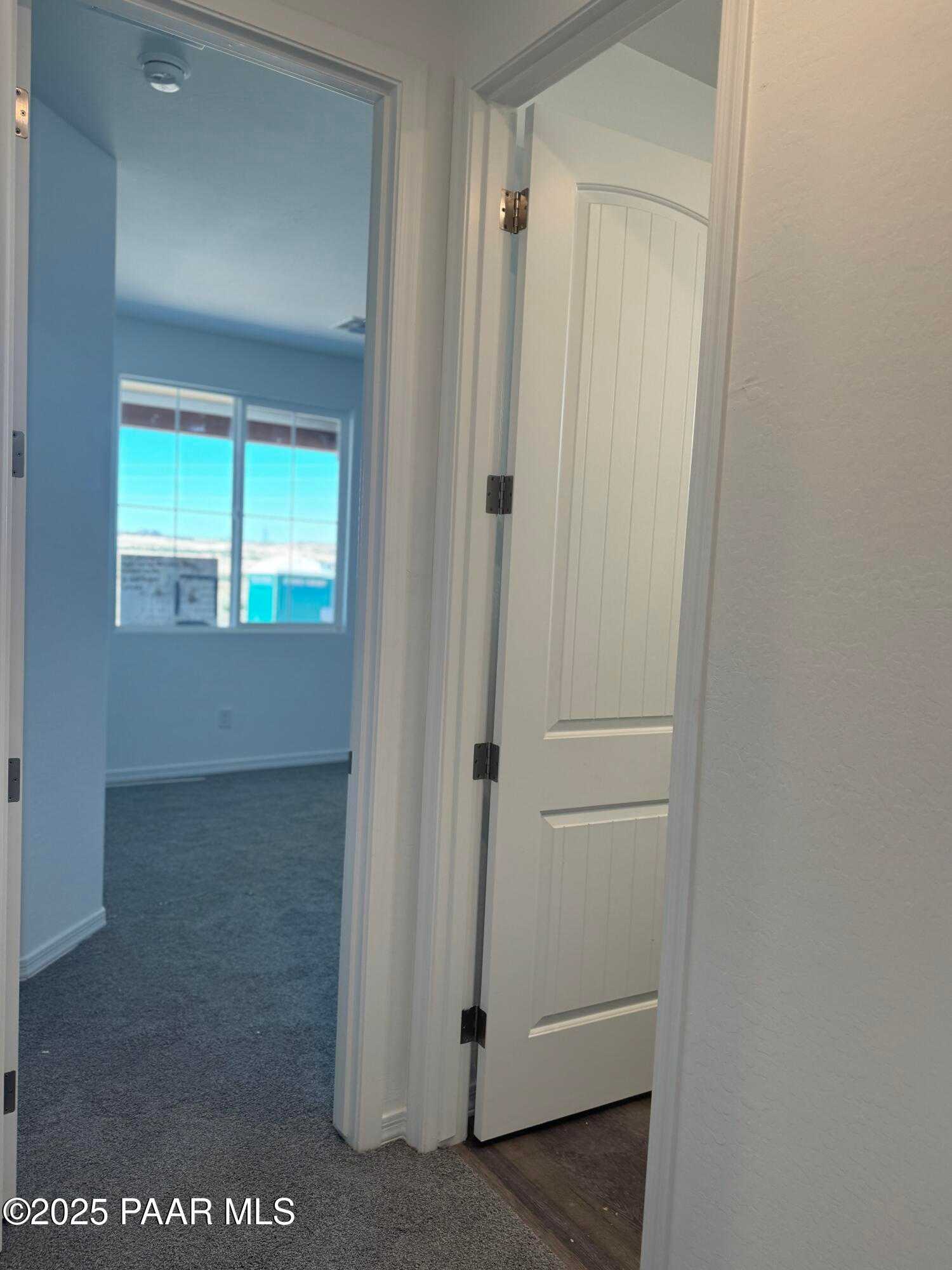 Bright hallway with open door to carpeted bedroom and sunlit window in Davidson Homes The Sunrise II A, Prescott, Arizona