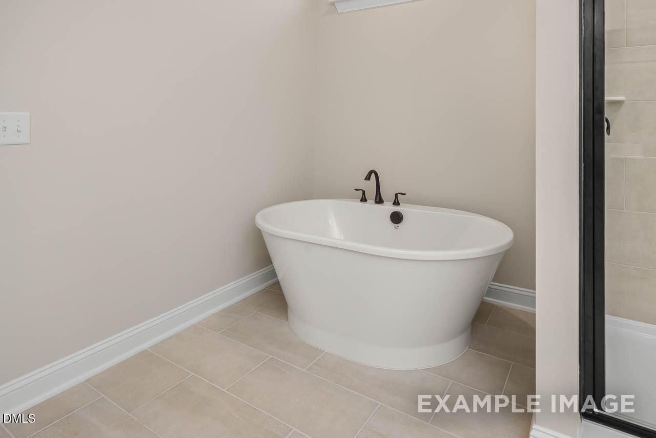 Elegant master bathroom featuring freestanding white oval tub, chrome faucets, and tiled glass shower in Davidson Homes Crawford D, Angier, NC