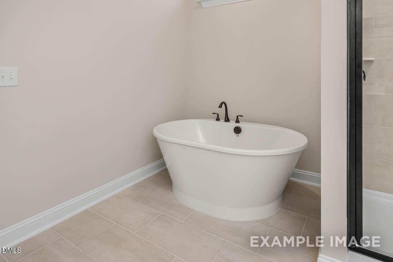 Elegant master bathroom featuring freestanding white oval tub, chrome faucets, and tiled glass shower in Davidson Homes Crawford D, Angier, NC