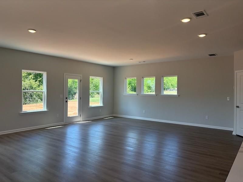Spacious open living area with hardwood floors, large windows, and glass door to backyard in Davidson Homes The Rabun A, Winder, Georgia