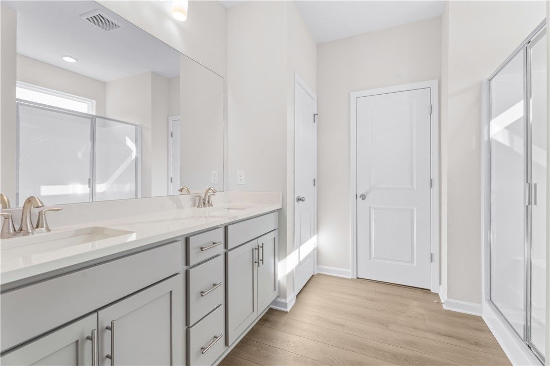 Modern master bathroom featuring double vanity, quartz counters, glass shower in Davidson Homes The Luna B, Opelika, Alabama