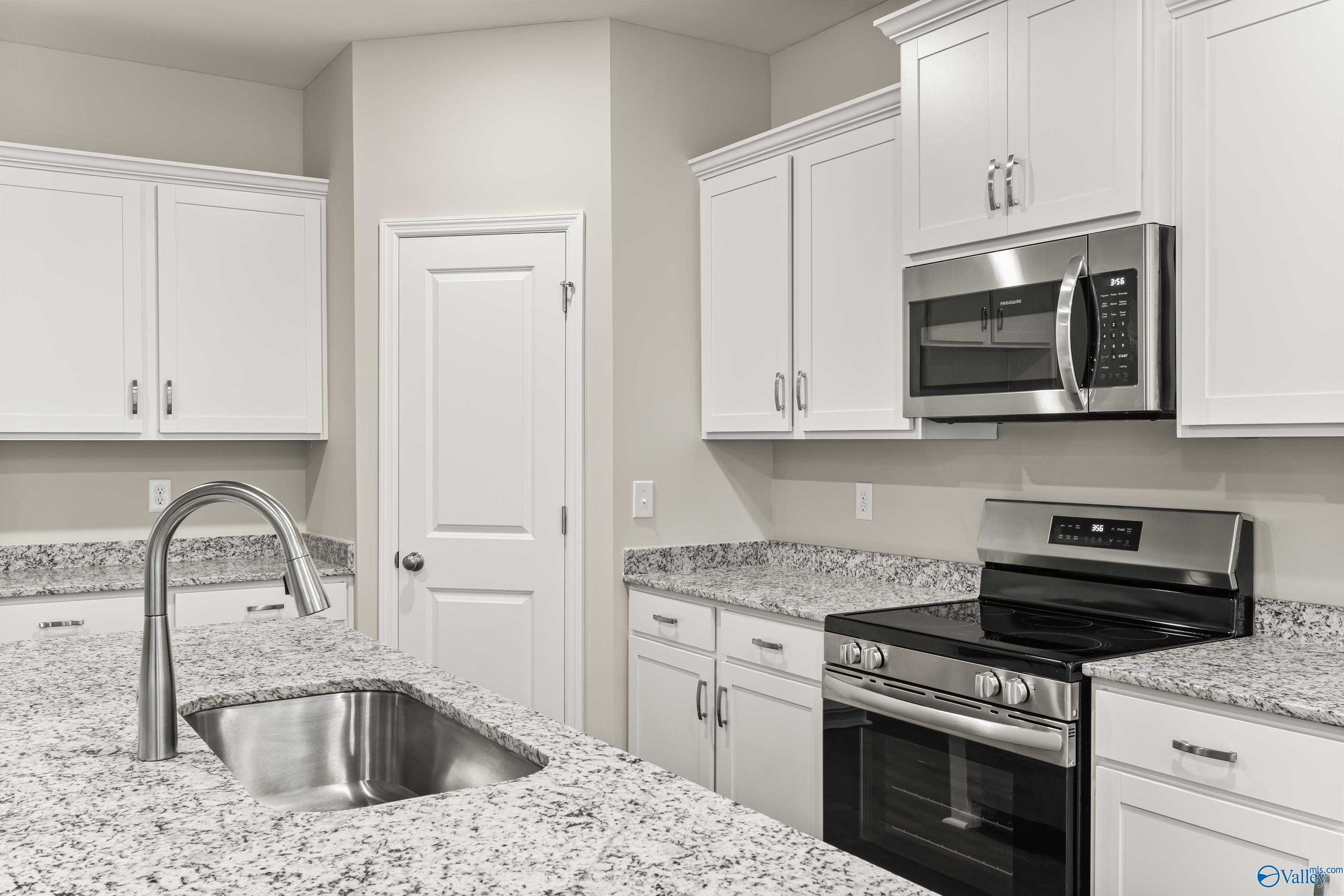 Modern white kitchen with granite countertops, stainless appliances in Davidson Homes The Phoenix, Fayetteville, TN