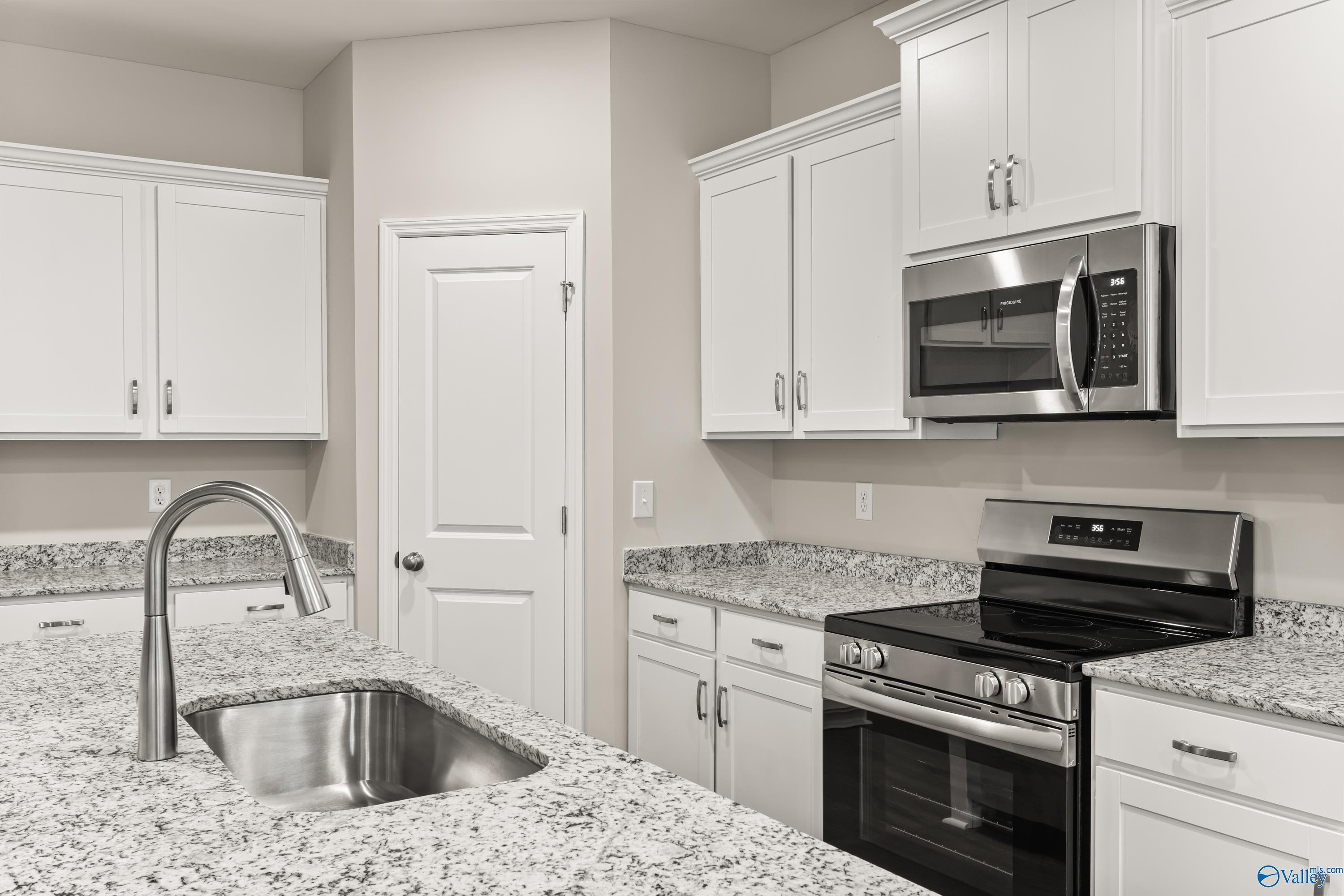Modern white kitchen with granite countertops, stainless steel appliances and sink in Davidson Homes The Phoenix, Fayetteville, TN
