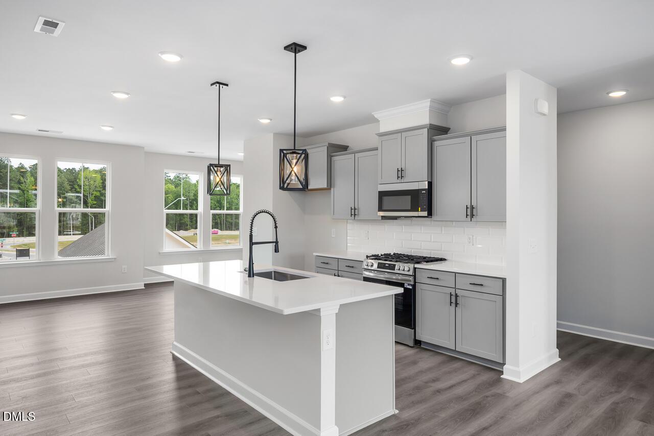 Modern kitchen with grey cabinets, quartz island, and pendant lighting in The Mitchell floor plan, Knightdale, NC.