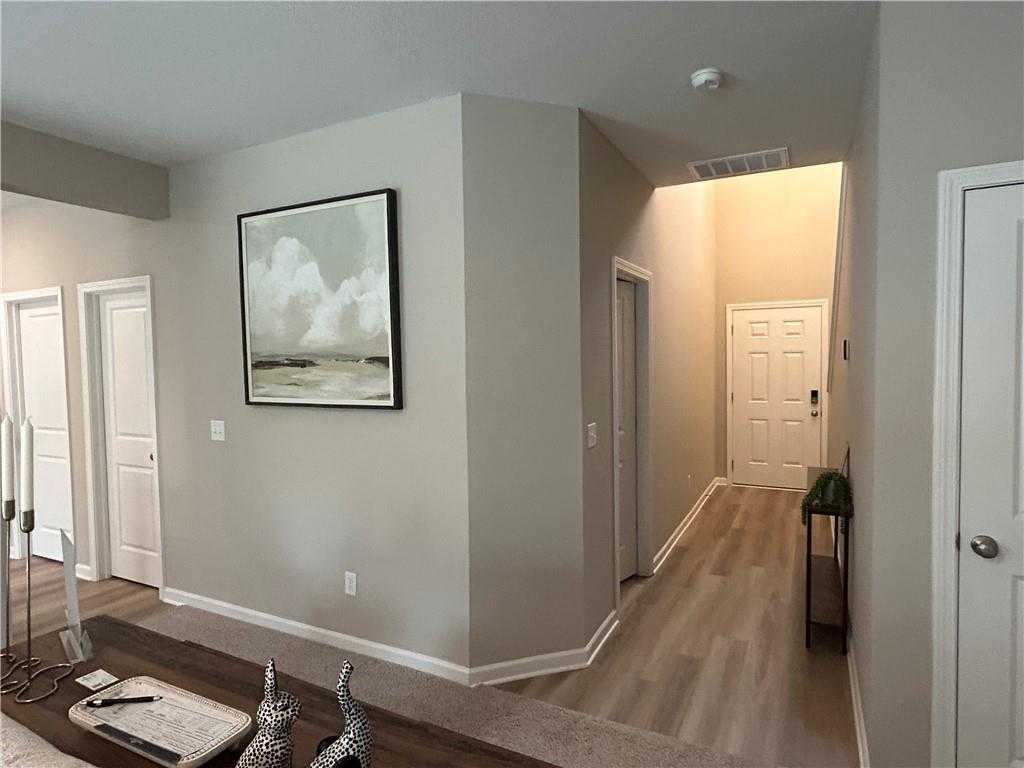 Elegant hallway with abstract cloud artwork, luxury vinyl plank flooring, and white doors in Davidson Homes The Bartlett, Phenix City