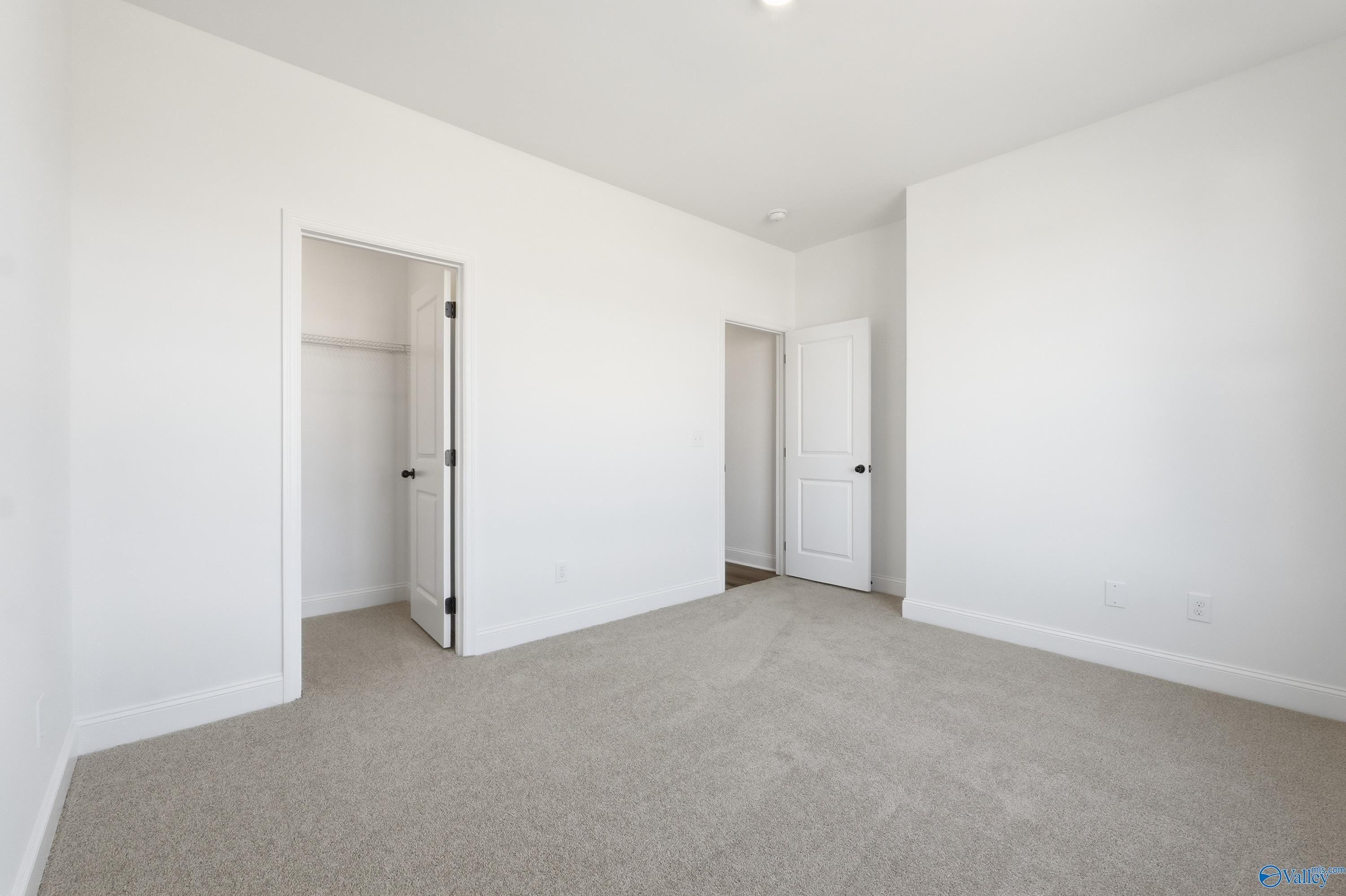 Spacious secondary bedroom with white walls, beige carpet, open walk-in closet in Davidson Homes The Rockford D, Hazel Green, Alabama
