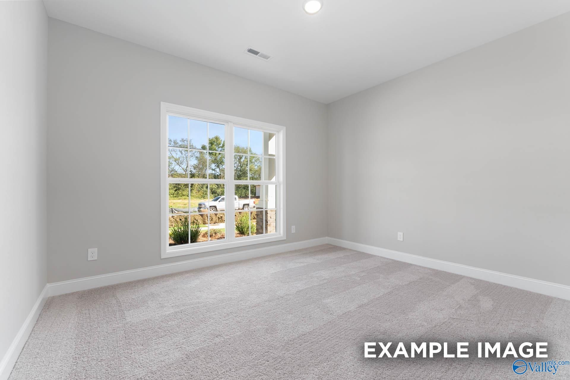 Bright empty secondary bedroom with large sunny window and neutral gray walls in Davidson Homes The Daphne D, Meridianville
