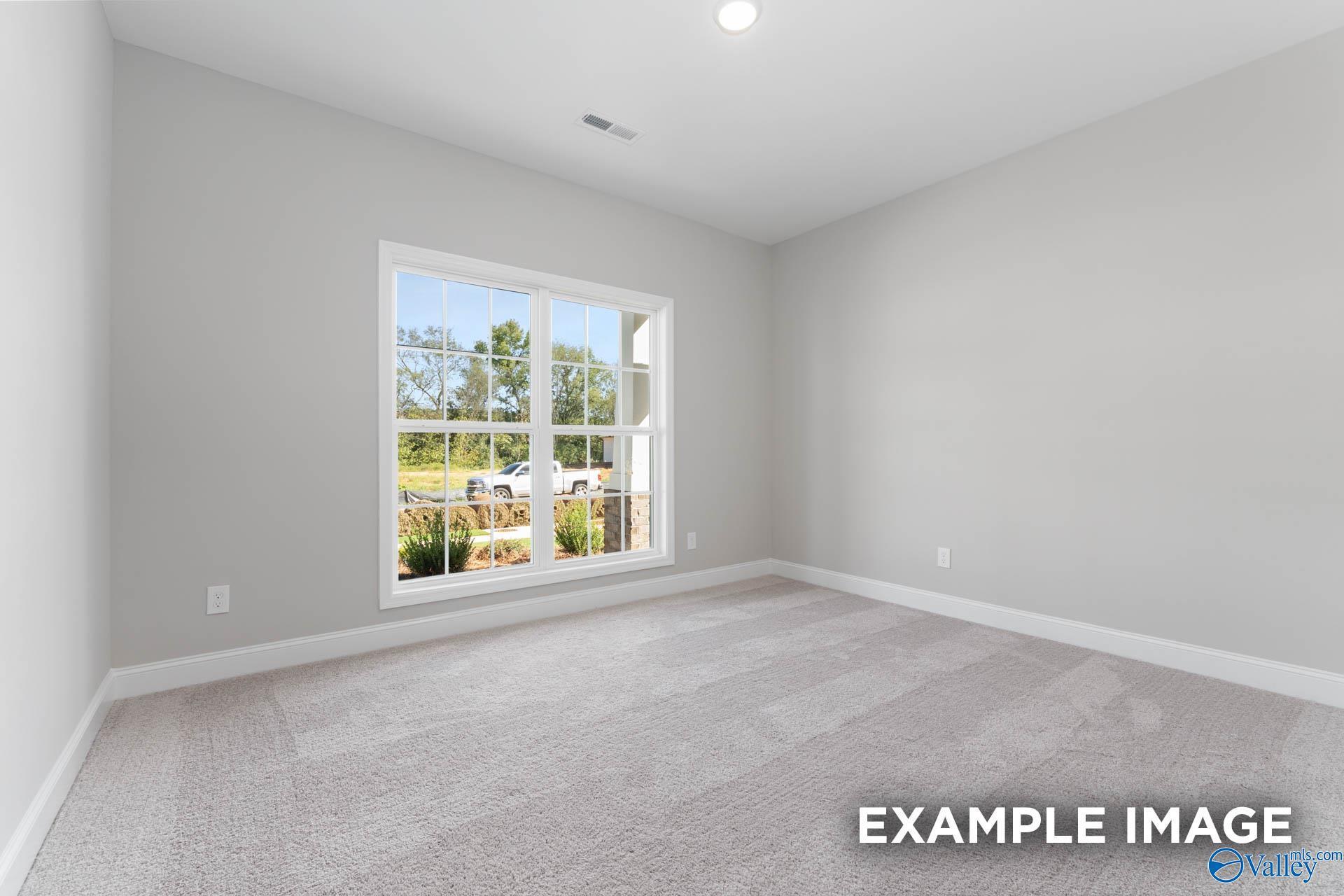 Bright empty secondary bedroom with large sunny window and neutral gray walls in Davidson Homes The Daphne D, Meridianville