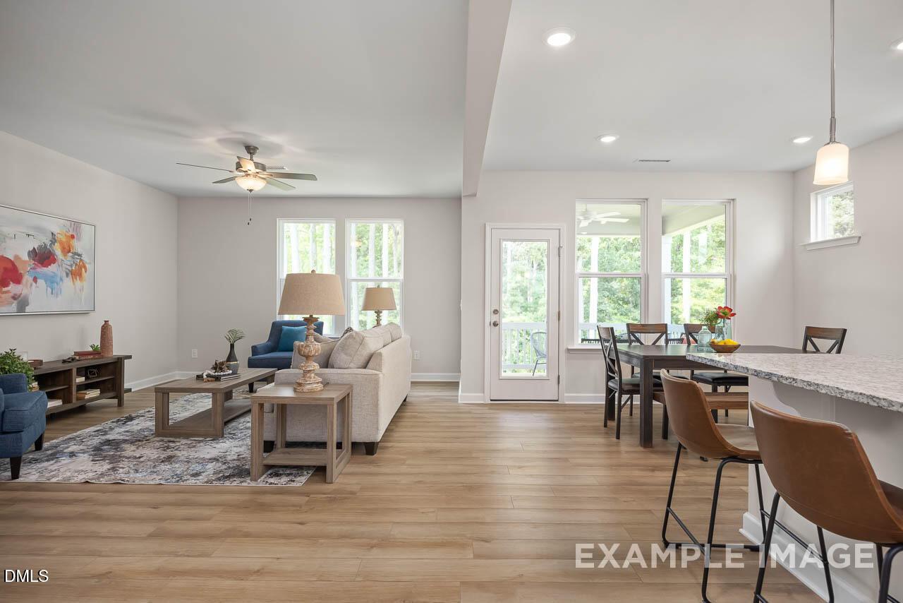 Spacious open living and dining area with beige sofa, wooden table, granite island, hardwood floors in Davidson Homes Willow D, Lillington NC