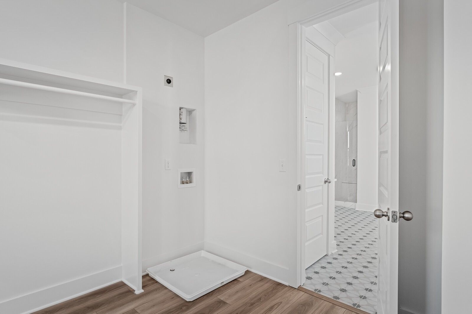 Bright laundry room with hardwood floors, open shelving, washer/dryer hookups, and adjacent walk-in shower in The Alston A, Murfreesboro