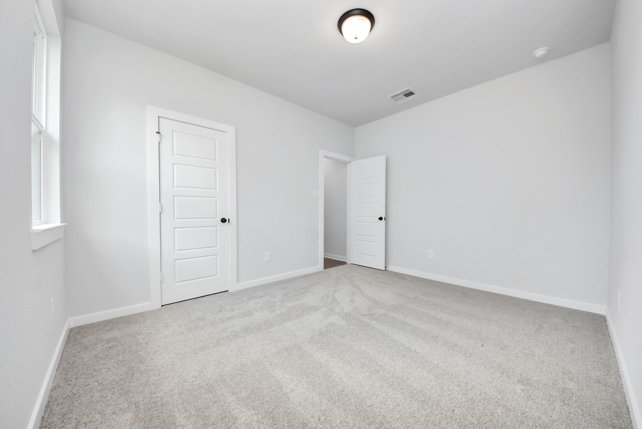 Bright, spacious secondary bedroom with plush carpet in The Daphne F floor plan at Sundance Cove, Crosby, Texas.
