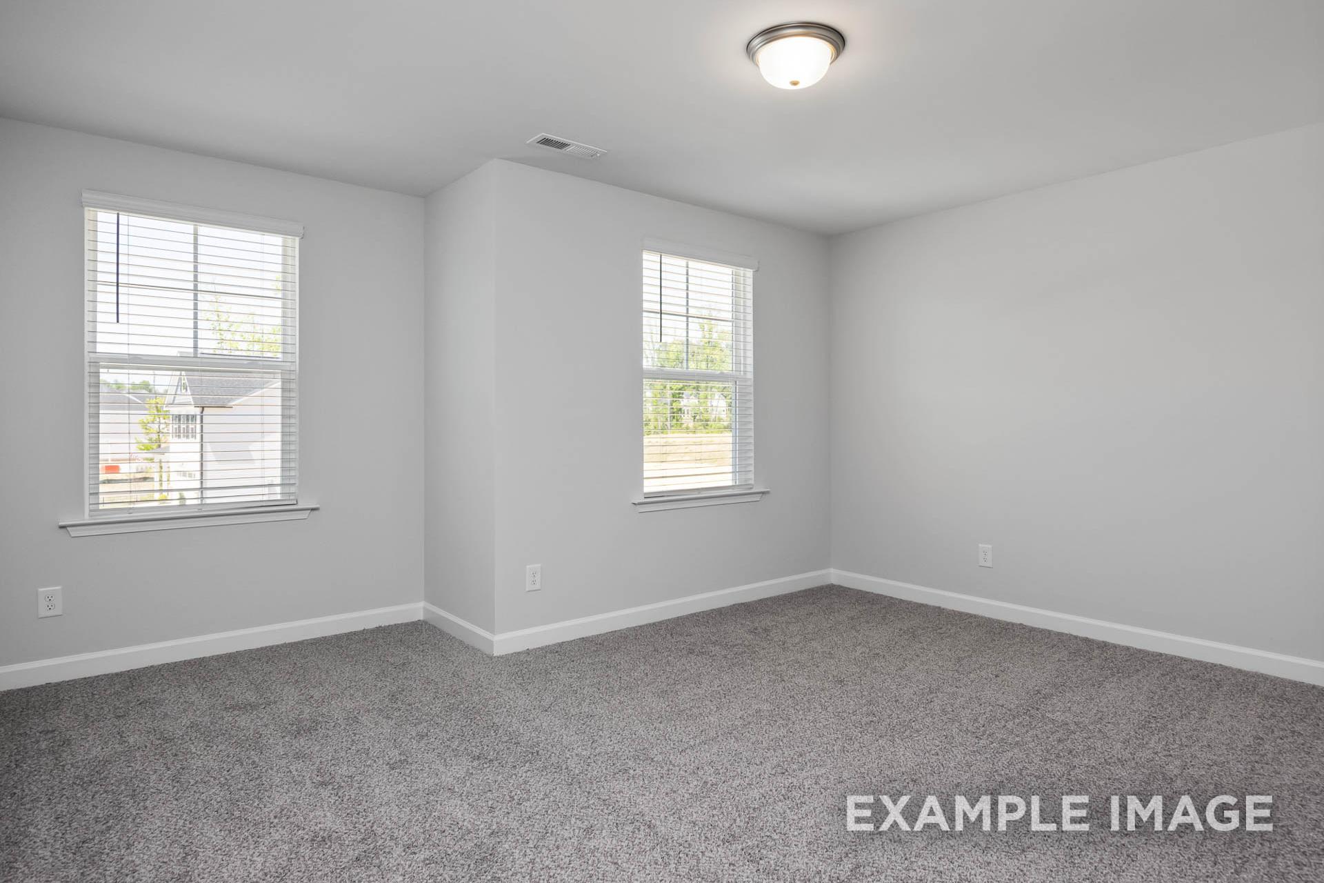 Spacious upstairs bedroom in The Preston B with gray carpet, white walls, blinds, and corner windows