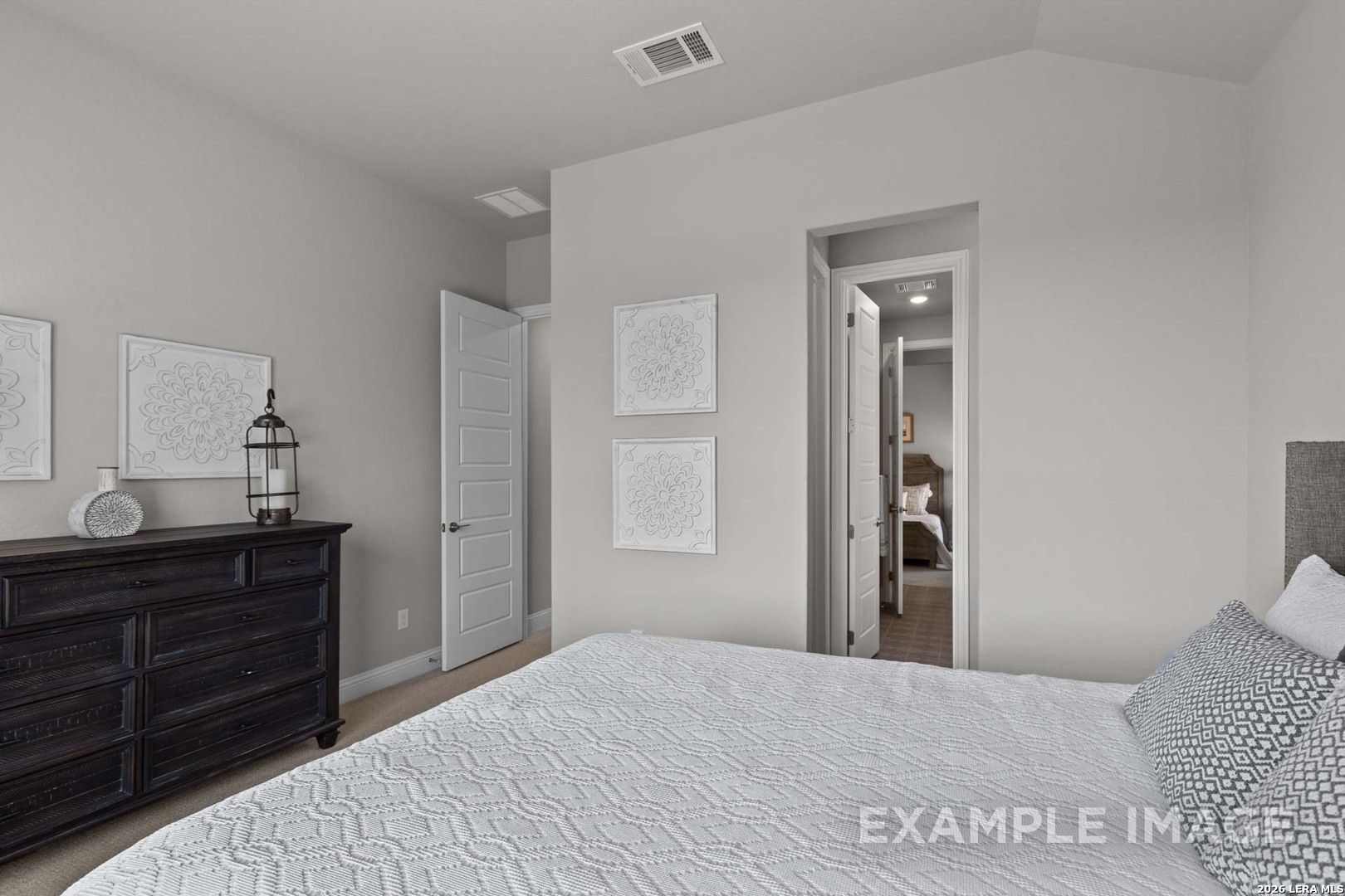 Bright bedroom with dark dresser and neutral decor in The Garner C floor plan by Davidson Homes in Castroville, Texas.