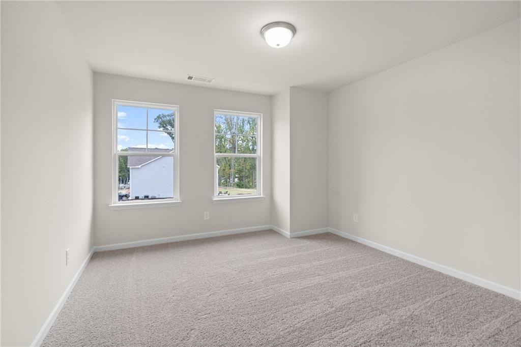 Bright secondary bedroom with plush gray carpet, large windows, and neutral walls in Davidson Homes The Marion B, Kennesaw, GA