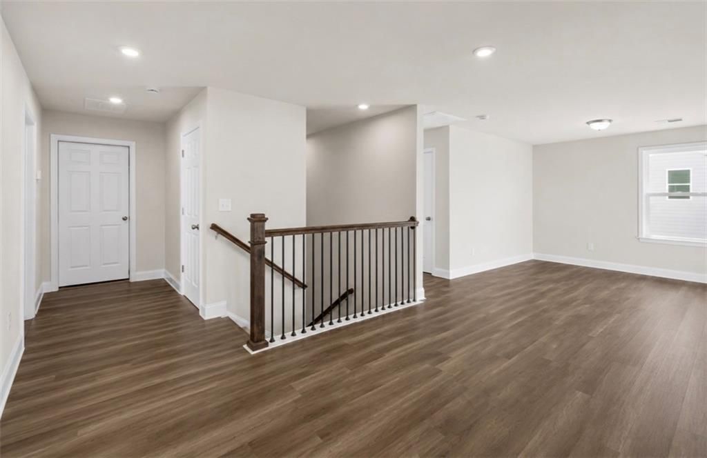 Spacious upper-level landing with wood-style flooring and modern staircase in The Ash C floor plan at Wehunt Meadows.