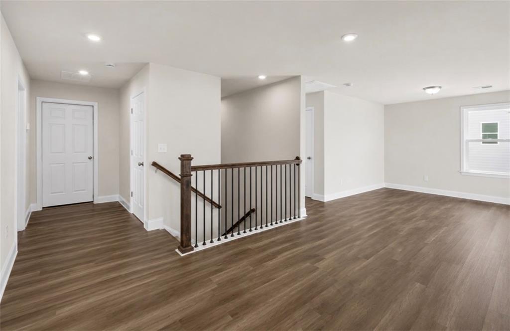 Spacious upper-level landing with wood-style flooring and modern staircase in The Ash C floor plan at Wehunt Meadows.