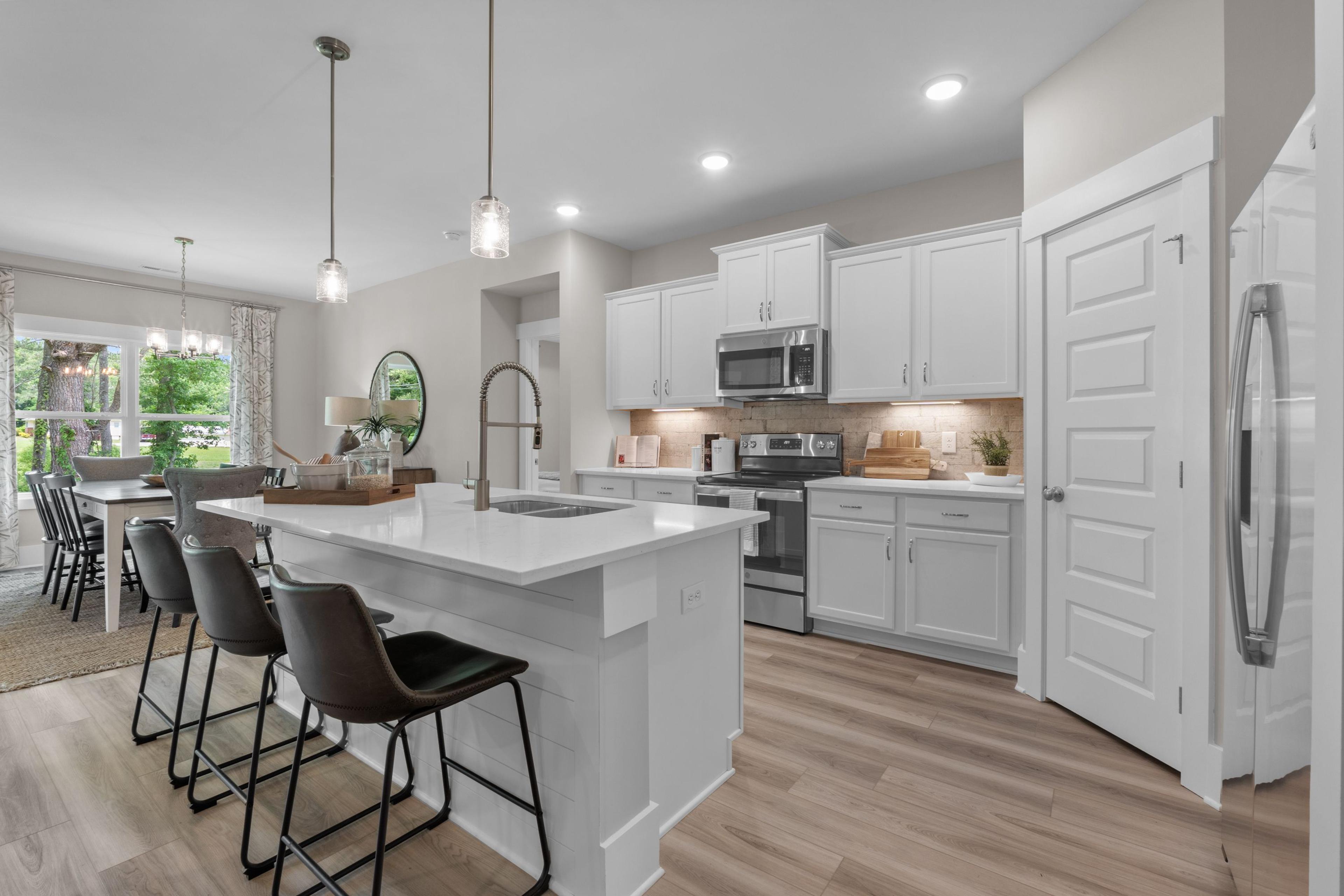 Spacious modern kitchen at The Highlands in Arab Alabama with white island, bar stools, pendant lights, and stainless appliances