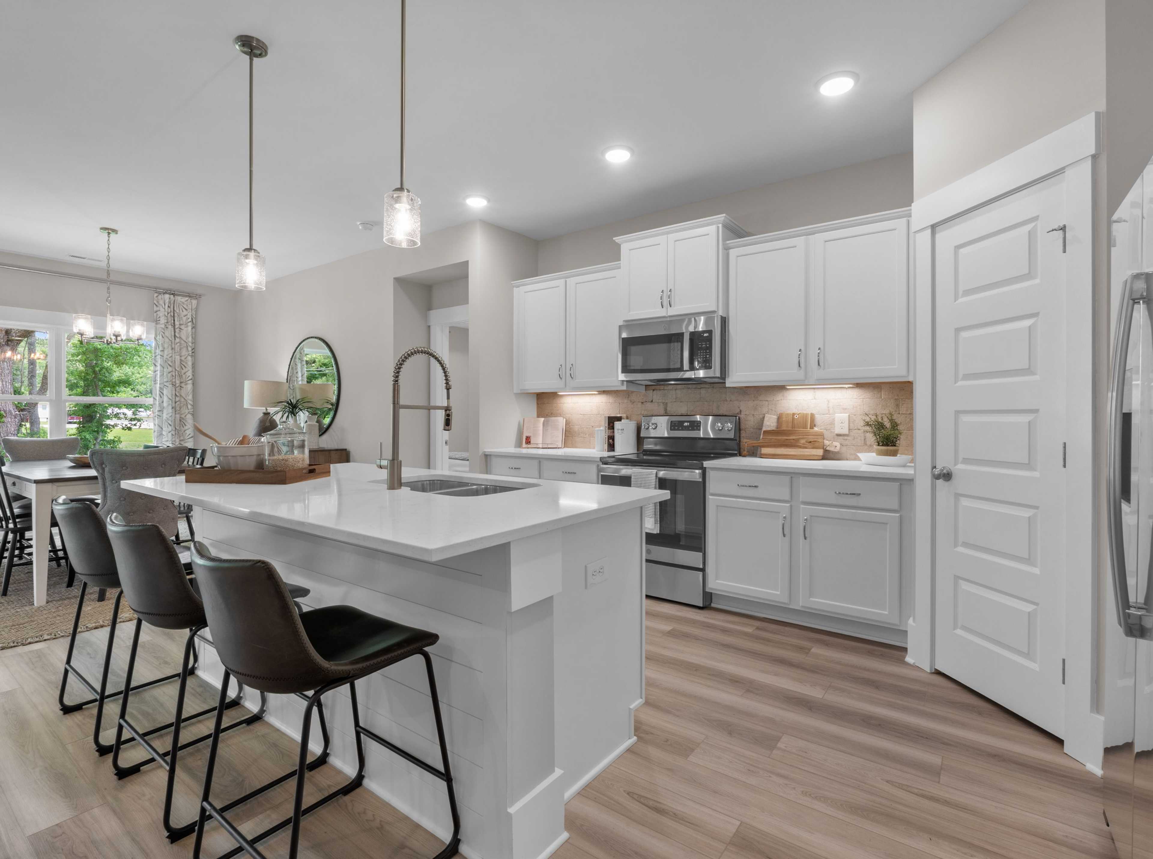 Spacious modern kitchen at The Highlands in Arab Alabama with white island, bar stools, pendant lights, and stainless appliances