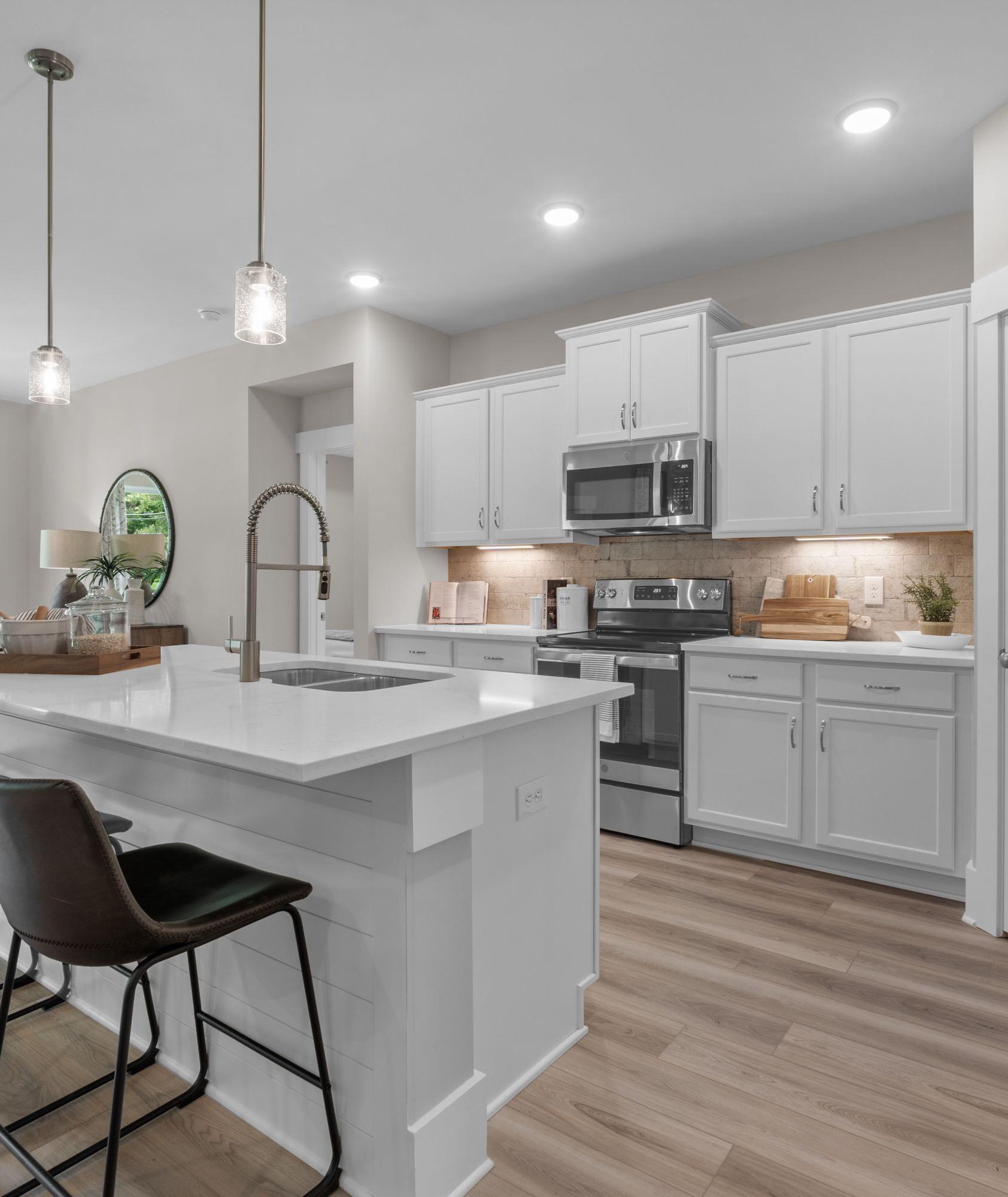 Spacious modern kitchen at The Highlands in Arab Alabama with white island, bar stools, pendant lights, and stainless appliances