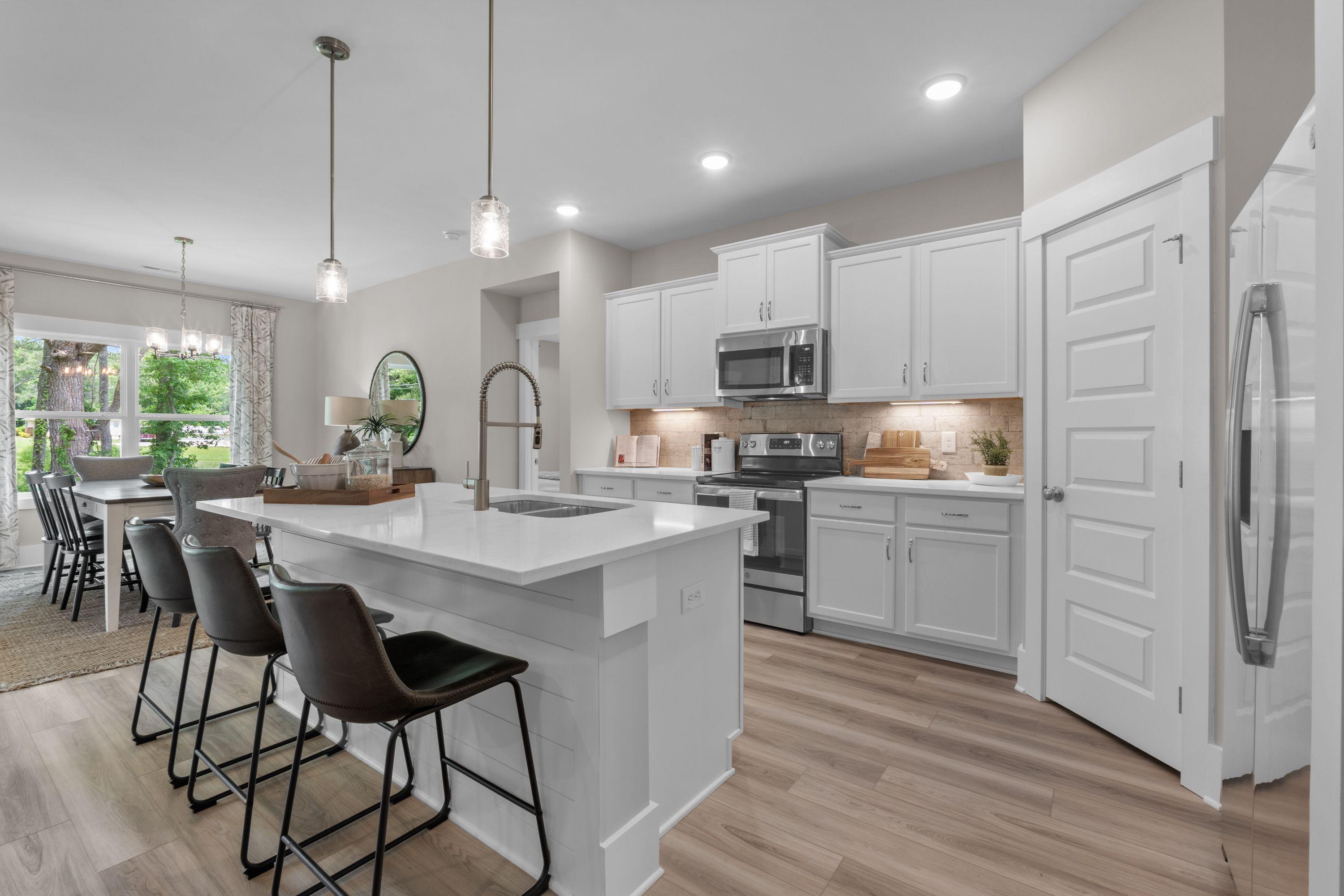 Spacious modern kitchen at The Highlands in Arab Alabama with white island, bar stools, pendant lights, and stainless appliances
