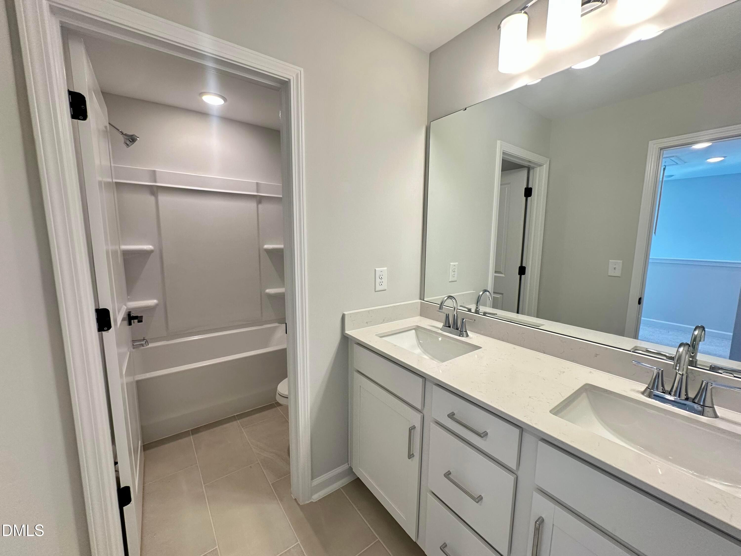 Modern double vanity with quartz countertop, white cabinets, and tub-shower combo in Davidson Homes The Avery, Knightdale, NC