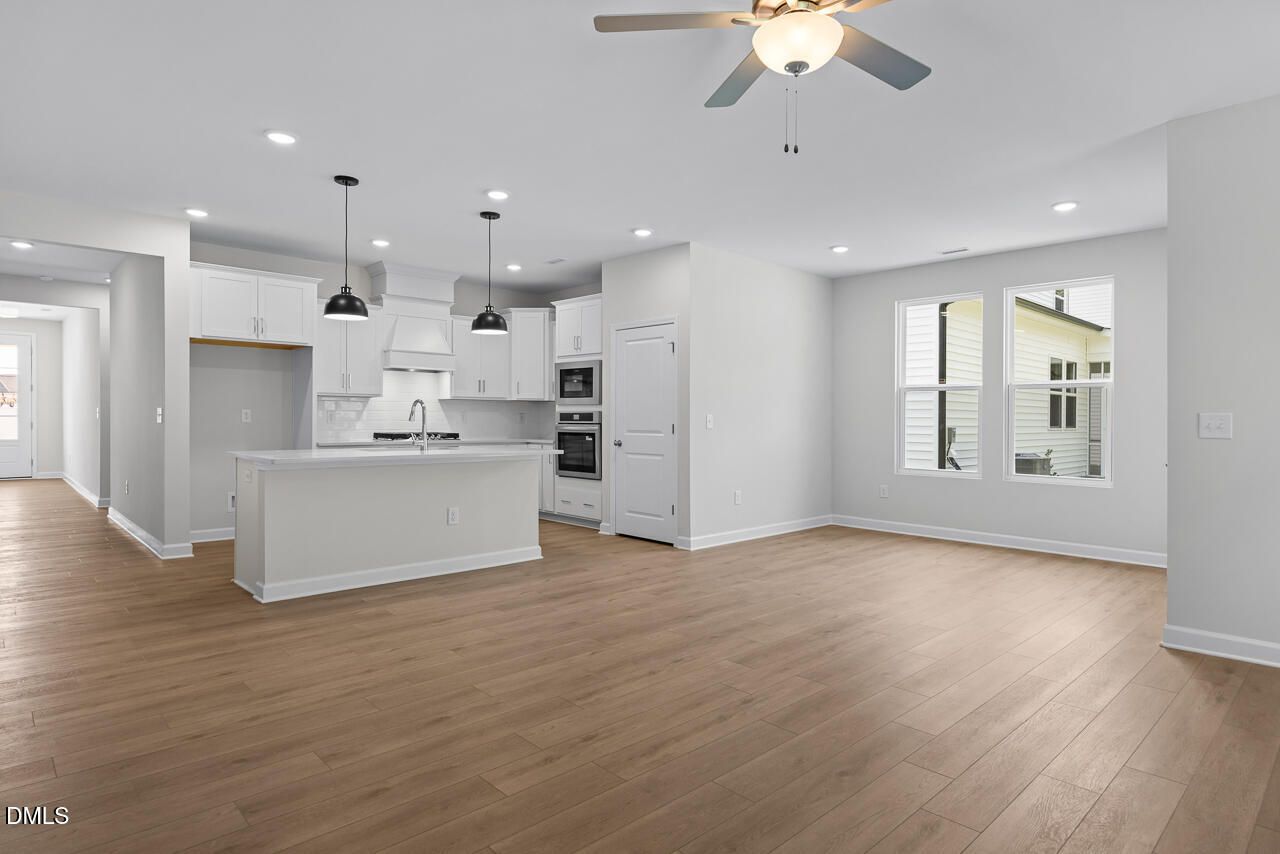 Open-concept kitchen with white cabinetry, island, and hardwood floors in Davidson Homes The Daphne D, Zebulon, NC