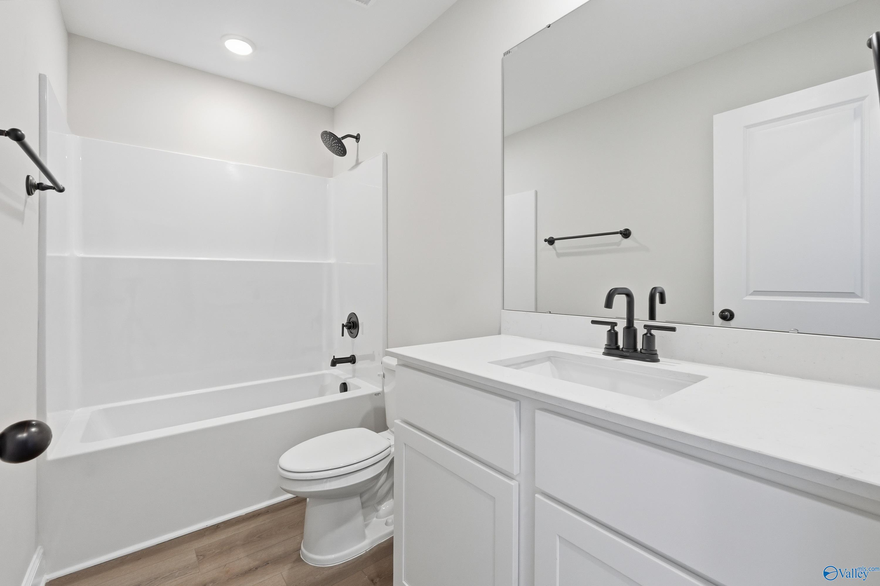 Bright white bathroom with tub-shower combo, black fixtures, and single vanity in Davidson Homes The Franklin V, Athens, Alabama