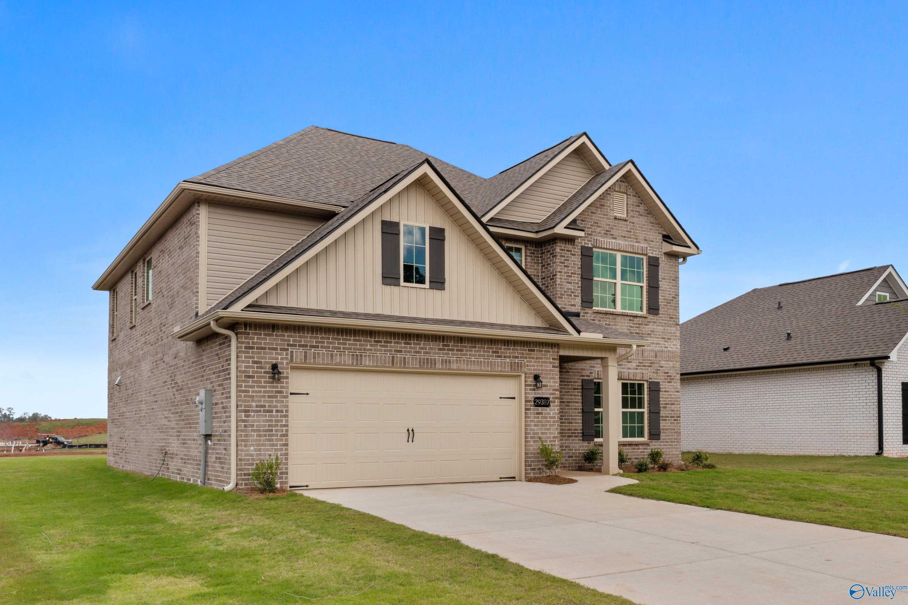 Two-story beige brick home with two-car garage and lush green lawn in Creekside, Harvest, Alabama by Davidson Homes