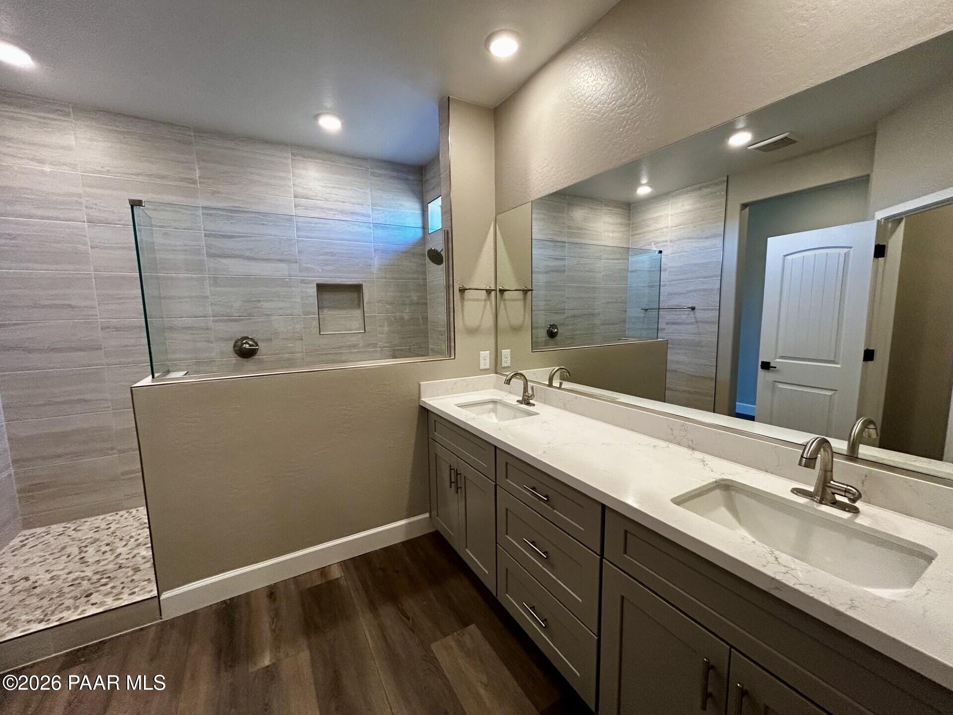 Modern primary bathroom with double vanity, quartz countertops, and walk-in tiled shower in The Harmony C, Pronghorn Ranch.