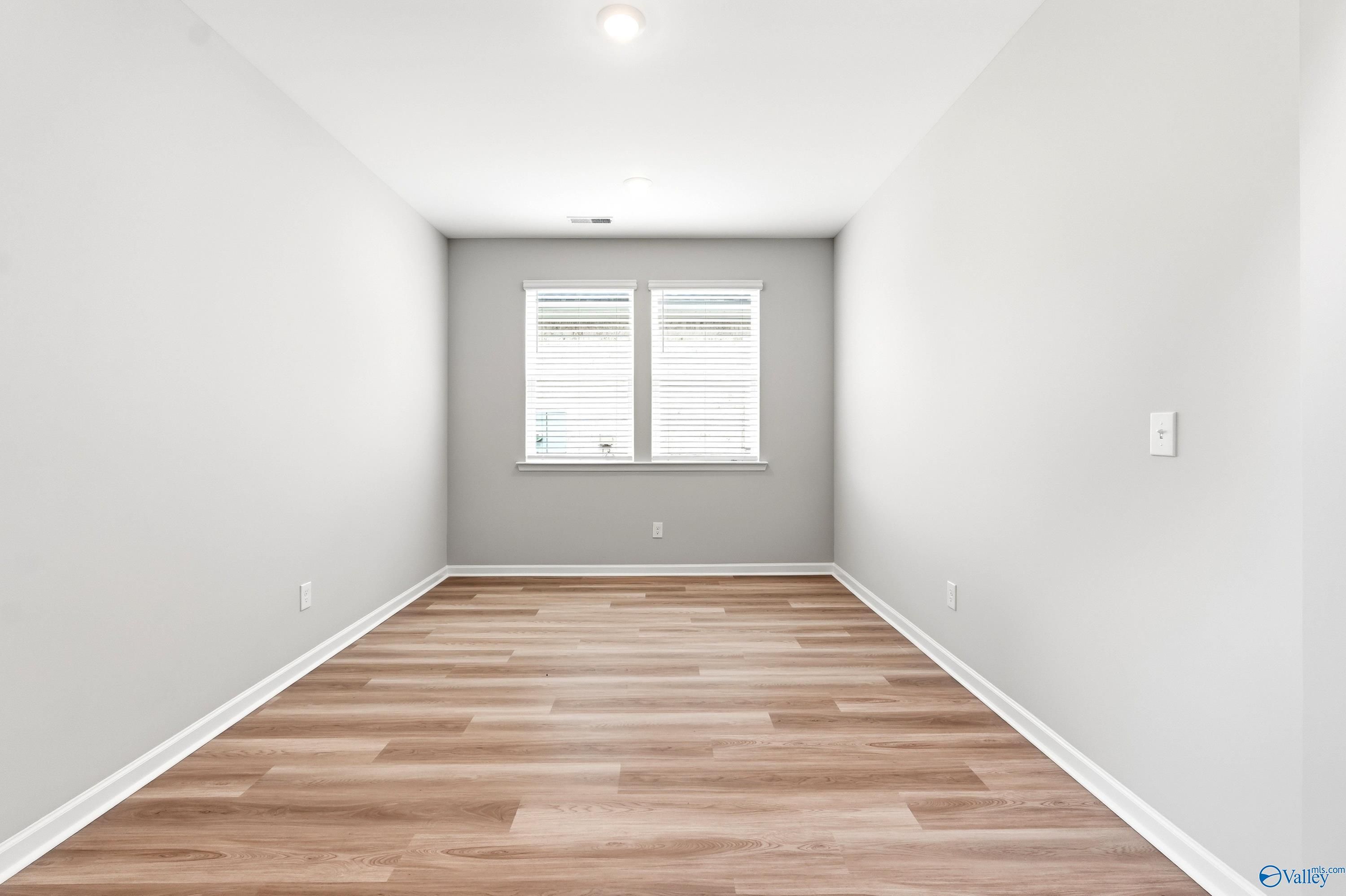 Spacious, neutral bedroom with wood-look flooring in The Dorado floor plan at Riverton Preserve, Huntsville, Alabama.