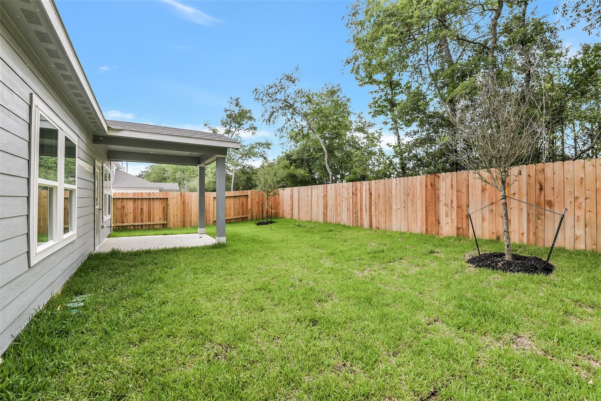 Covered back patio overlooking lush green backyard with privacy fence in Davidson Homes The Brazos F, Conroe, Texas