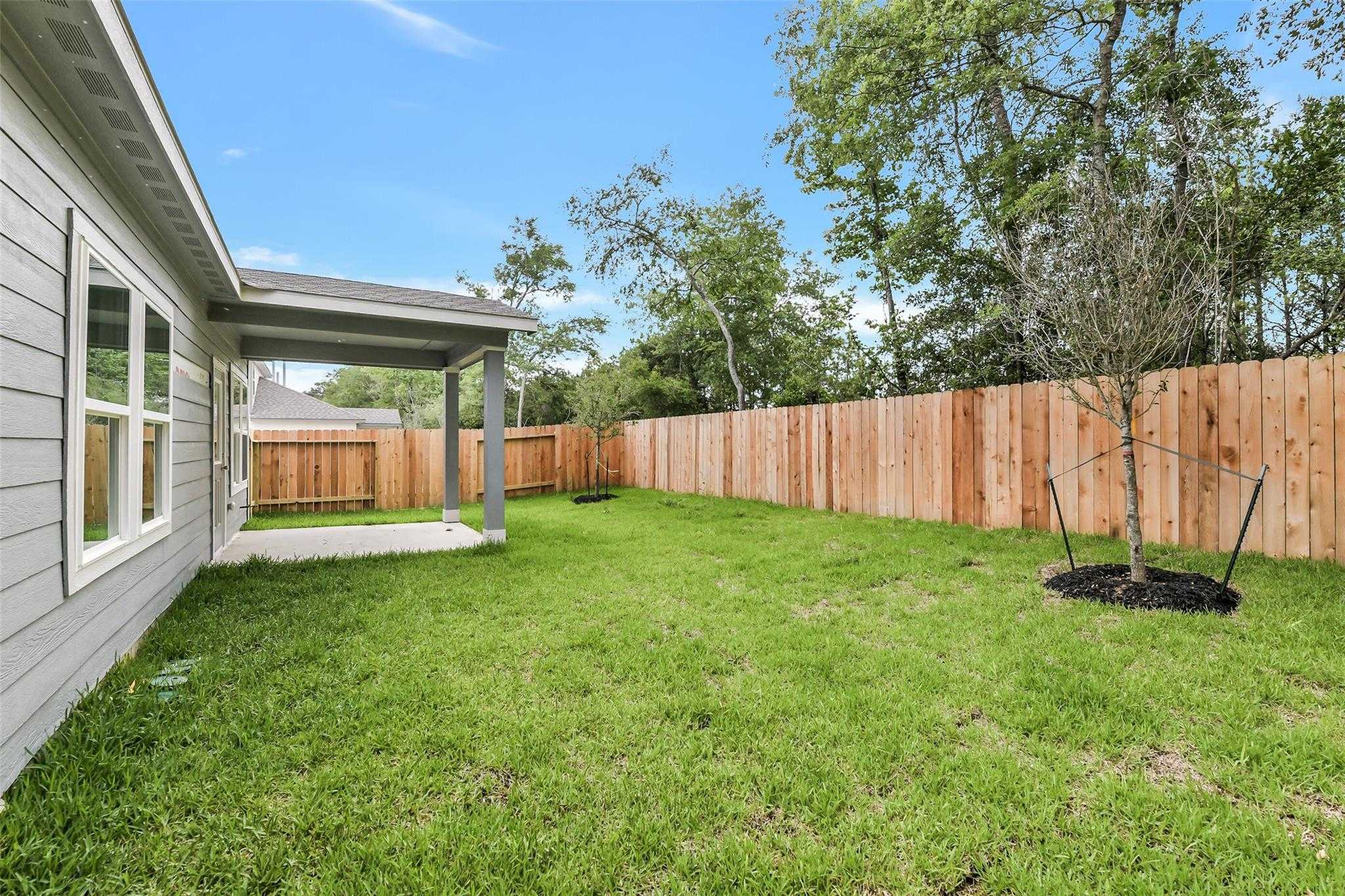 Covered back patio overlooking lush green backyard with privacy fence in Davidson Homes The Brazos F, Conroe, Texas