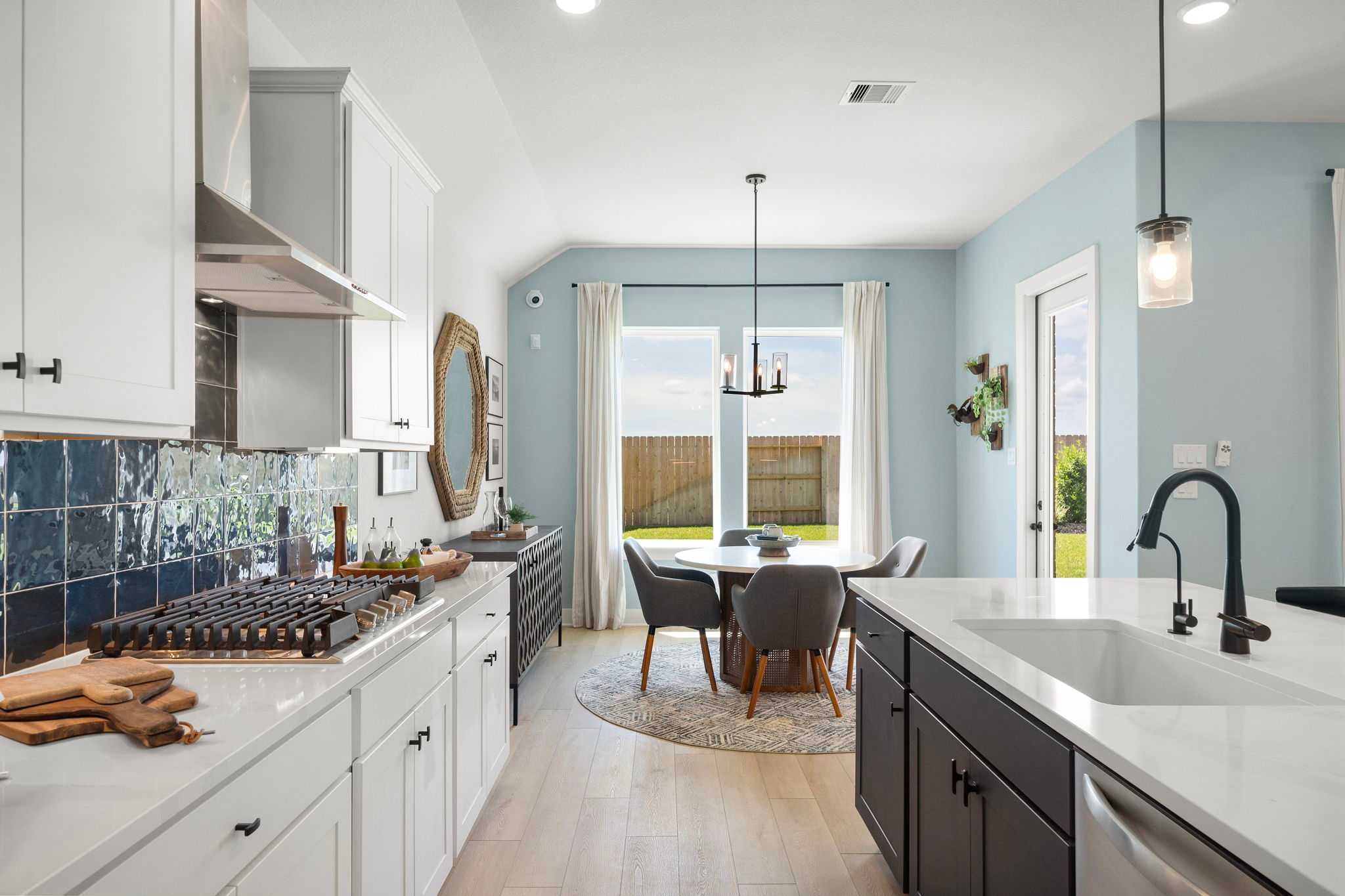 Open-concept kitchen dining area at Lago Mar in Texas City TX with white cabinets blue tile backsplash hardwood floors