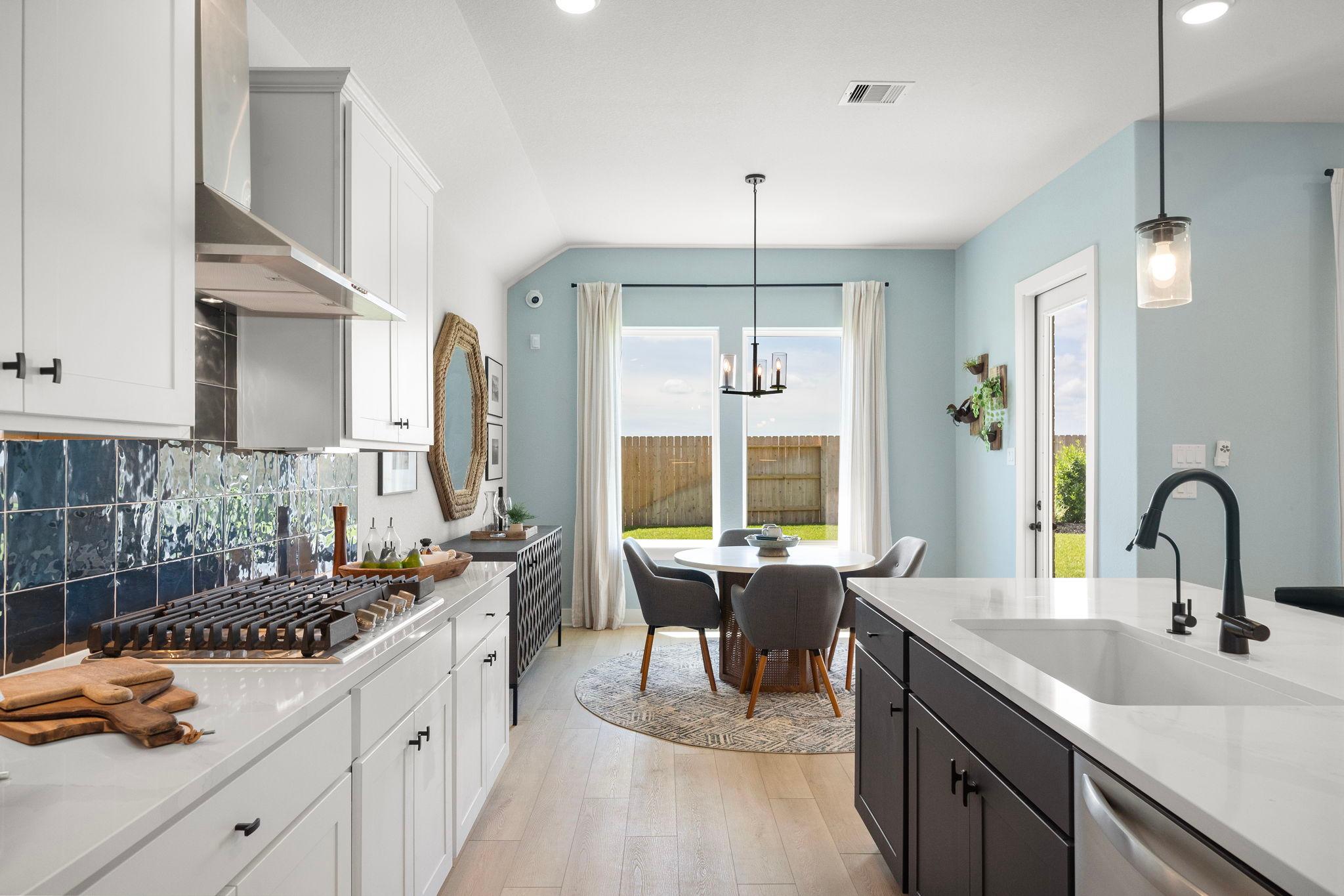 Open-concept kitchen dining area at Lago Mar in Texas City TX with white cabinets blue tile backsplash hardwood floors