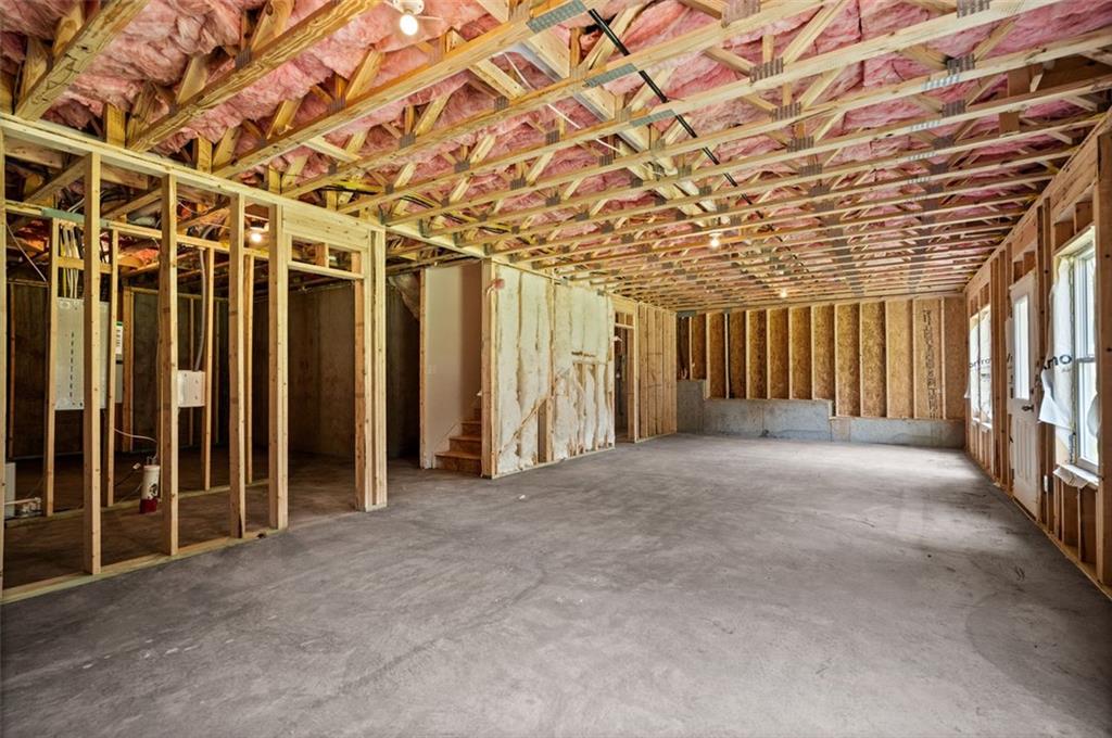 Unfinished basement with wood framing, pink insulation, exposed joists, and open concrete space in Davidson Homes The Hickory B at Wehunt Meadows, Hoschton, GA