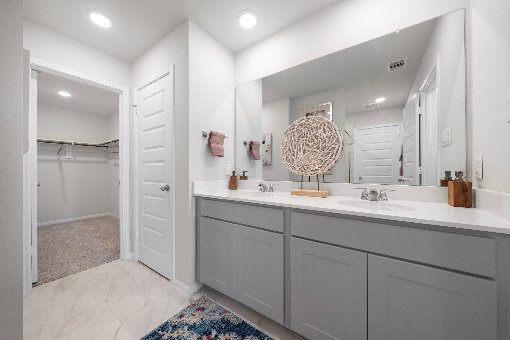 Spacious primary bathroom at Hill & Dale Ranch in Splendora, Texas with double gray vanity, quartz countertop, and walk-in closet