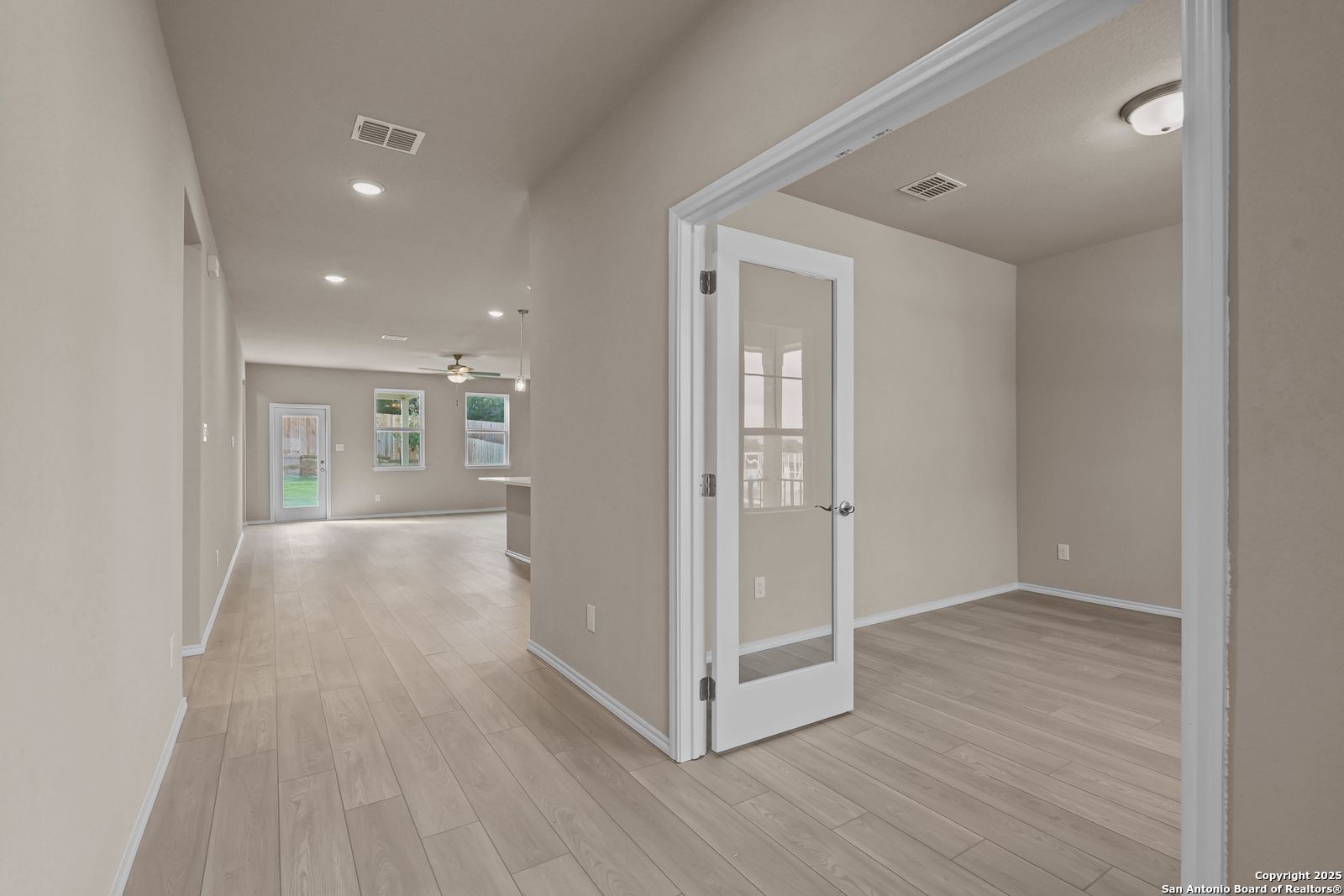 Bright hallway with light wood floors, glass doors, and recessed lights in Davidson Homes The Douglas G, San Antonio