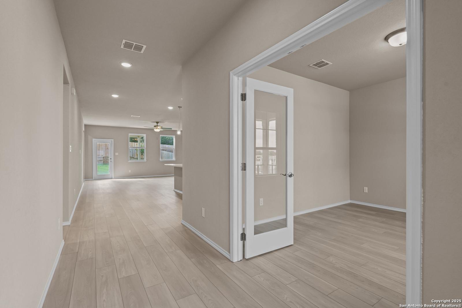 Bright hallway with light wood floors, glass doors, and recessed lights in Davidson Homes The Douglas G, San Antonio