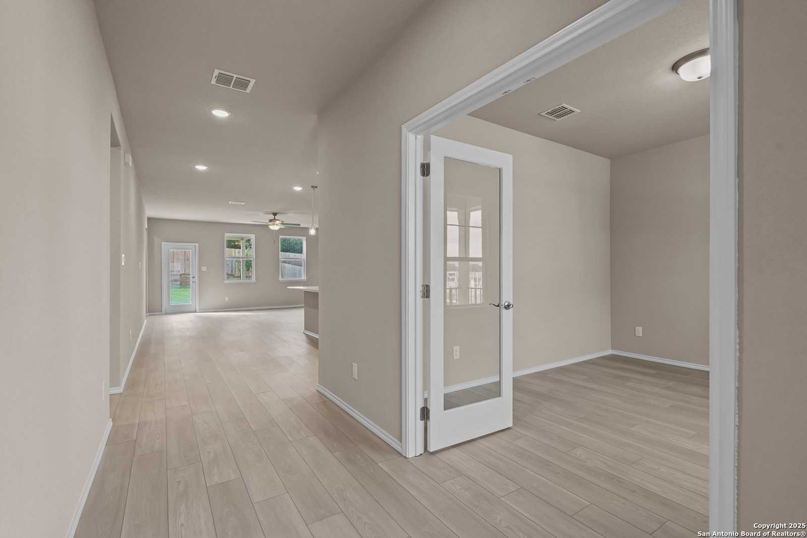 Bright hallway with light wood floors, glass doors, and recessed lights in Davidson Homes The Douglas G, San Antonio