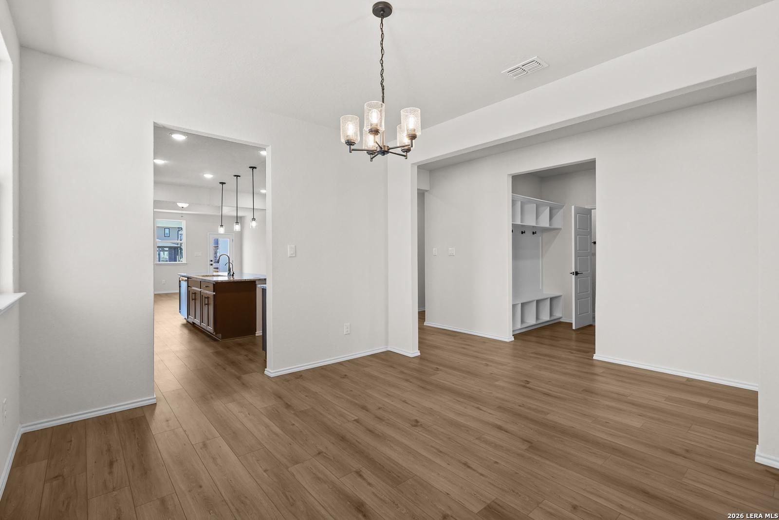 Bright dining area with chandelier and wood-look flooring in The Glenwood E floor plan by Davidson Homes, San Antonio, Texas