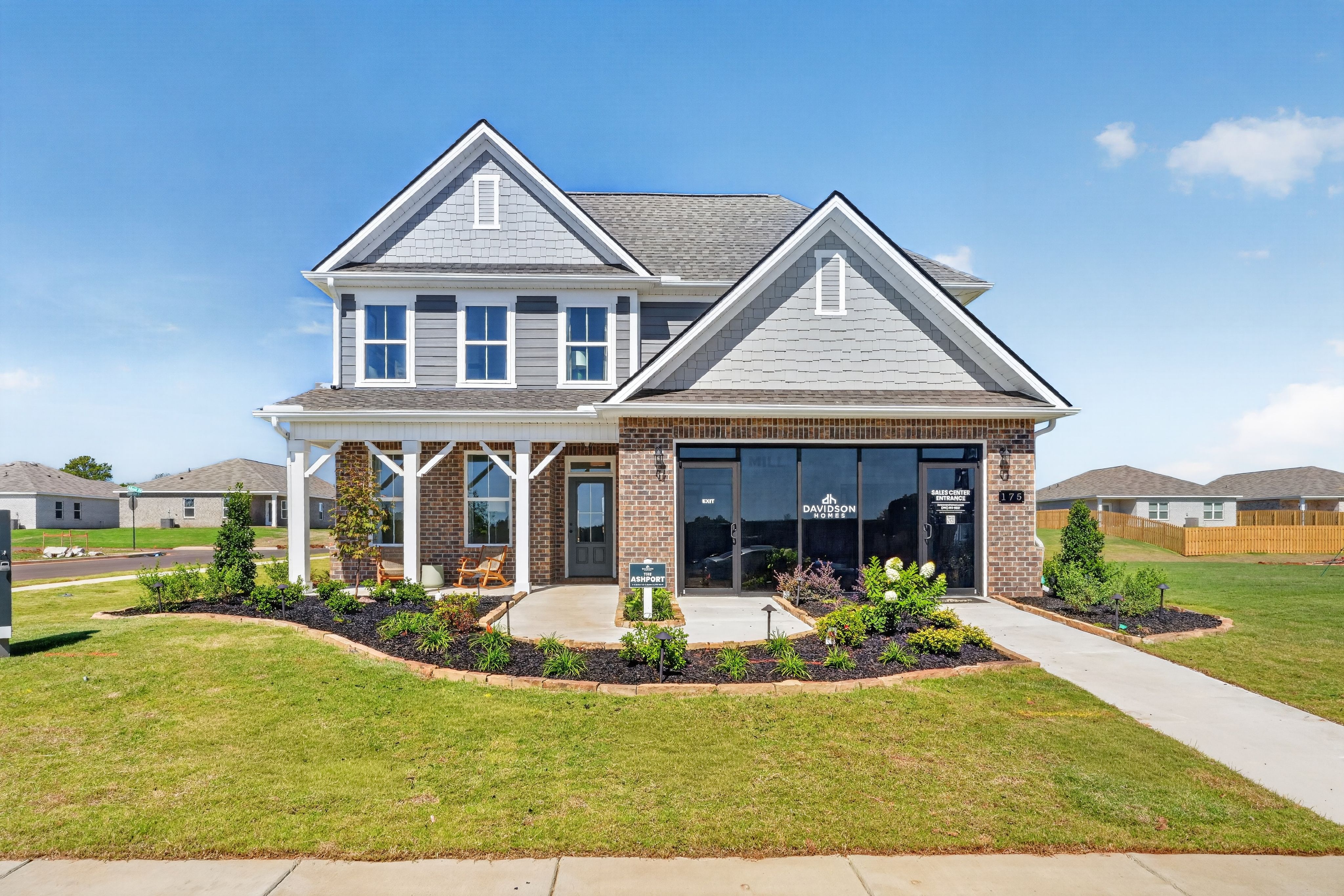 Two-story gray and brick Davidson Homes sales center at Evergreen Mill in Madison, Alabama with covered front porch and landscaped yard