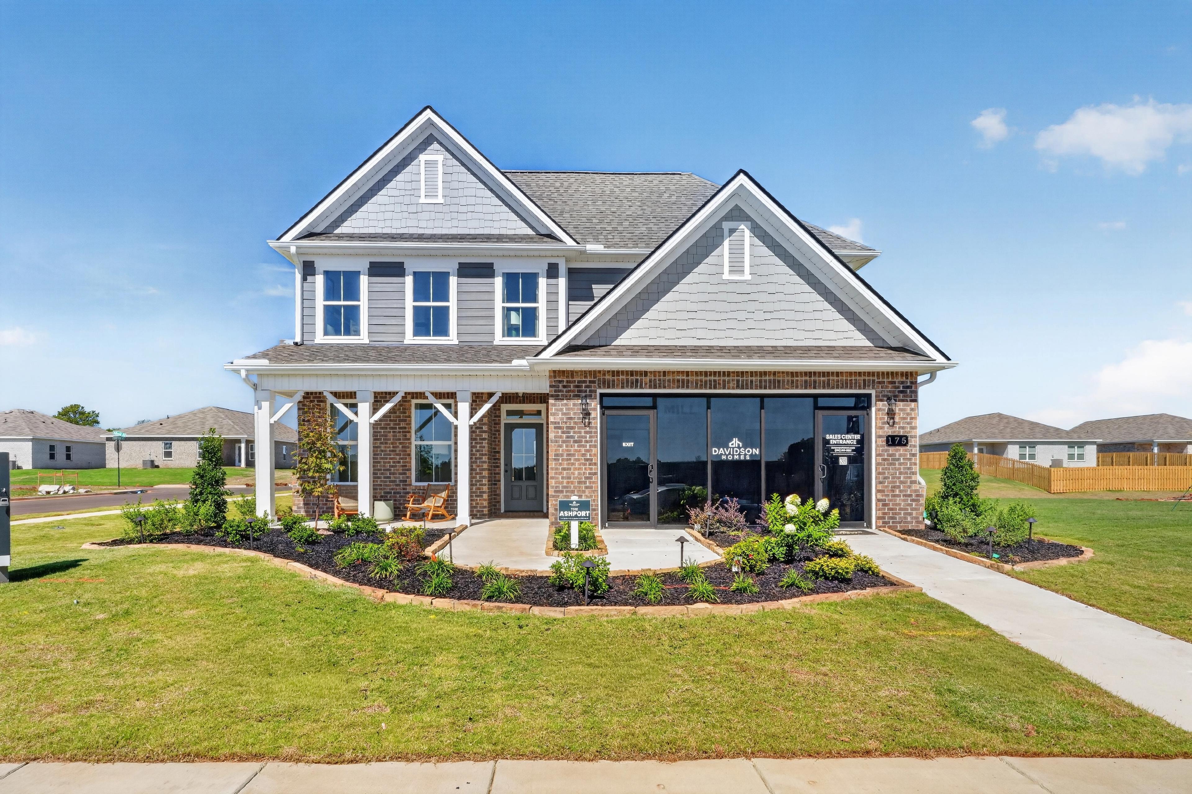 Two-story gray and brick Davidson Homes sales center at Evergreen Mill in Madison, Alabama with covered front porch and landscaped yard