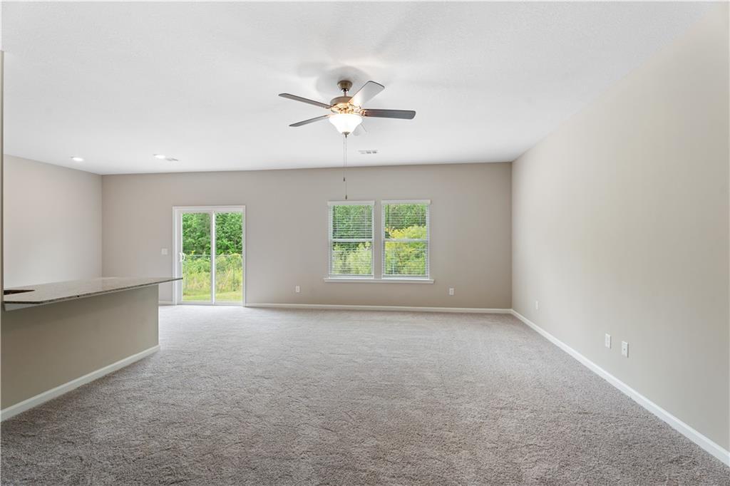 Open living area with ceiling fan, sliding doors to lush backyard, and breakfast bar in Davidson Homes The Bartlett, Phenix City, Alabama